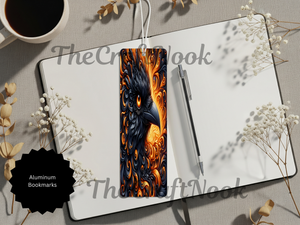 Handcrafted phoenix bookmarks displayed on a notebook with a pen, showcasing vibrant fire bird design and aluminum construction.