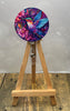 Hummingbird badge pulls displayed on a wooden easel, featuring vibrant floral design and colorful hummingbird.
