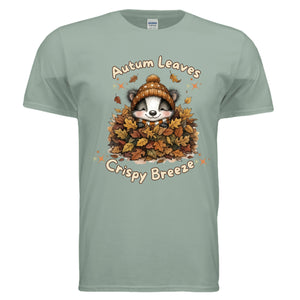 Autumn graphic tee in sage color featuring a cute raccoon surrounded by autumn leaves and the text 'Autumn Leaves Crispy Breeze'.