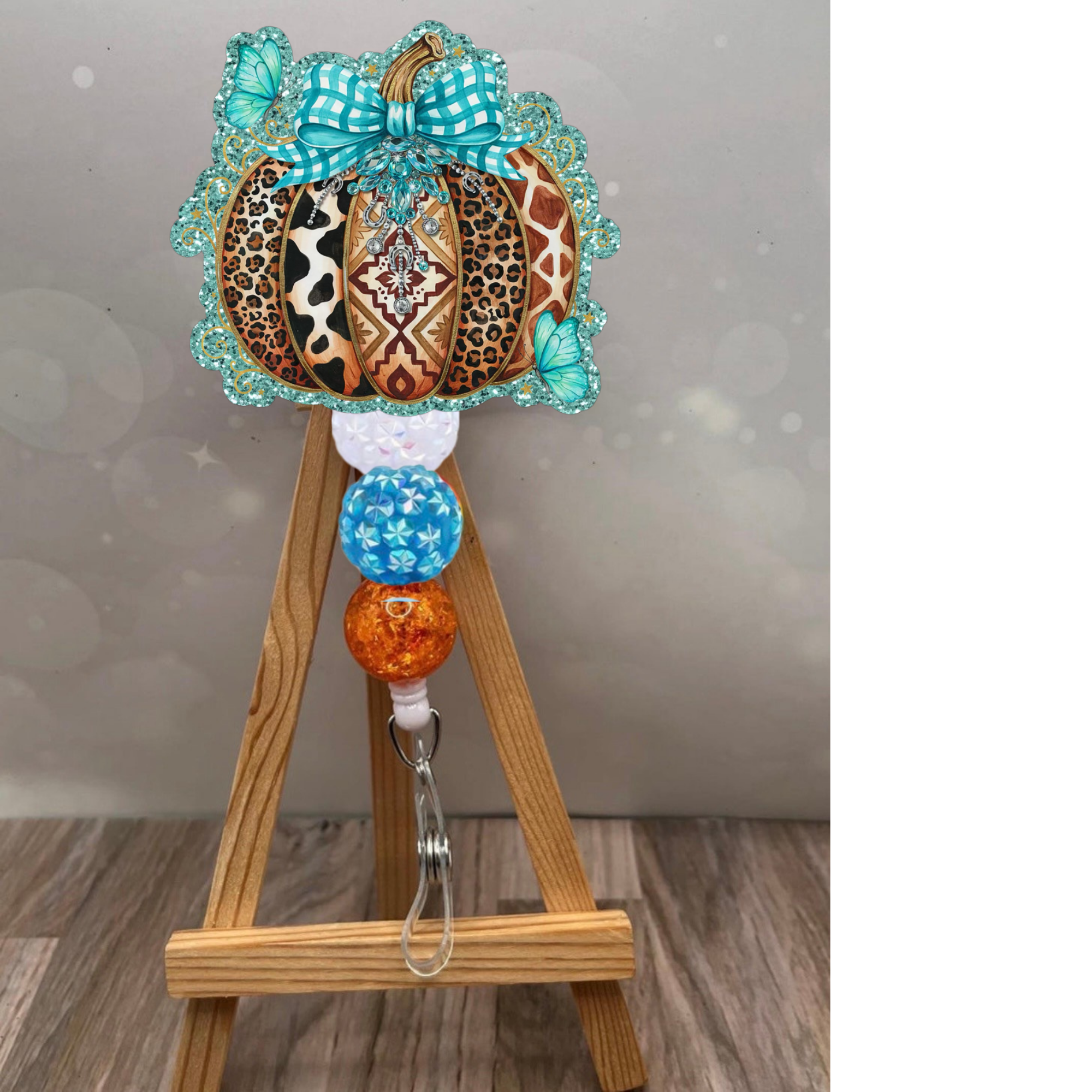Boho pumpkin badge reel featuring a colorful patchwork pumpkin, teal bow, and glitter accents on a retractable badge holder.