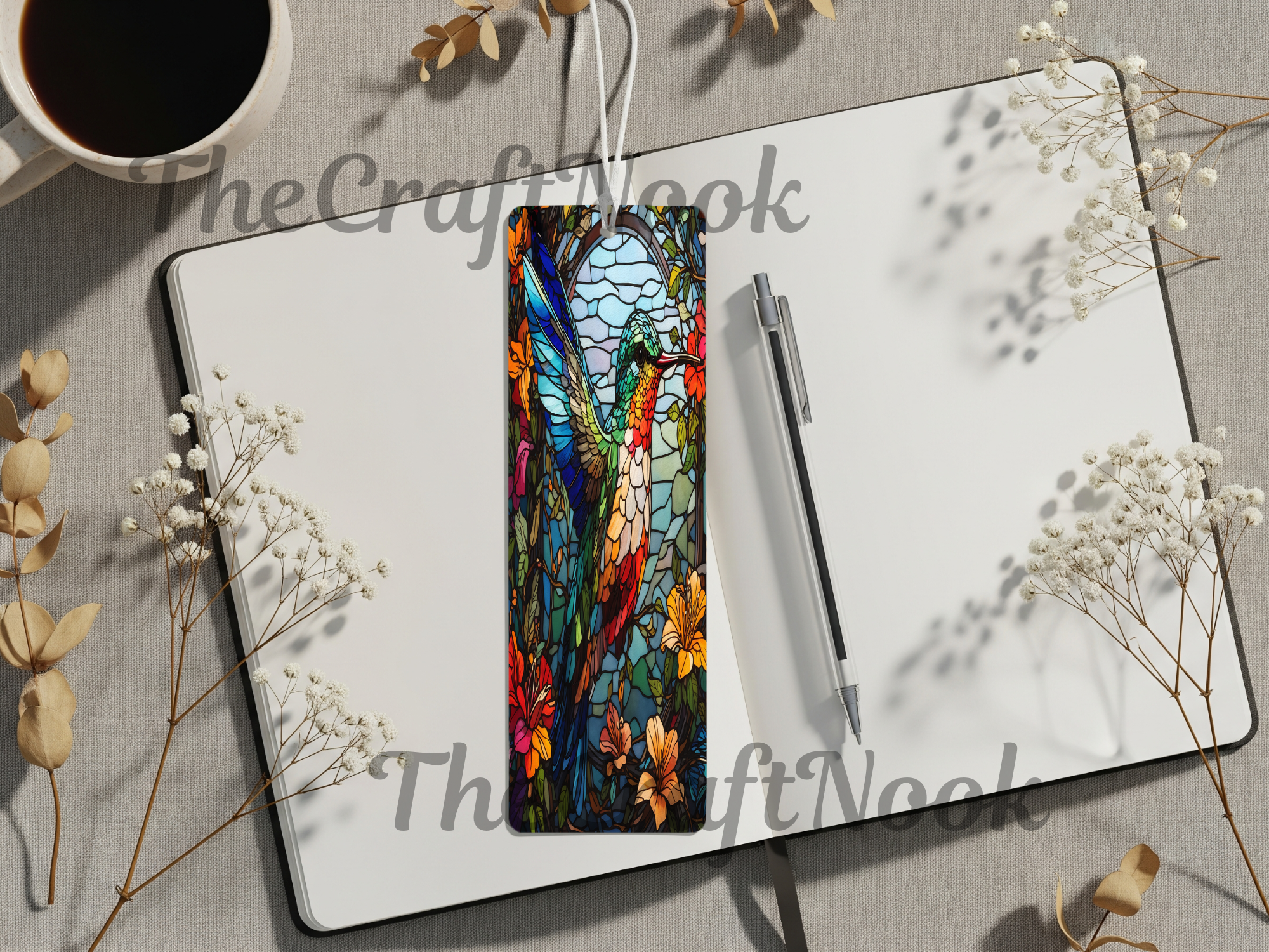 Hummingbird aluminum bookmarks showcasing vibrant colors and floral designs on a notebook with a coffee cup beside.