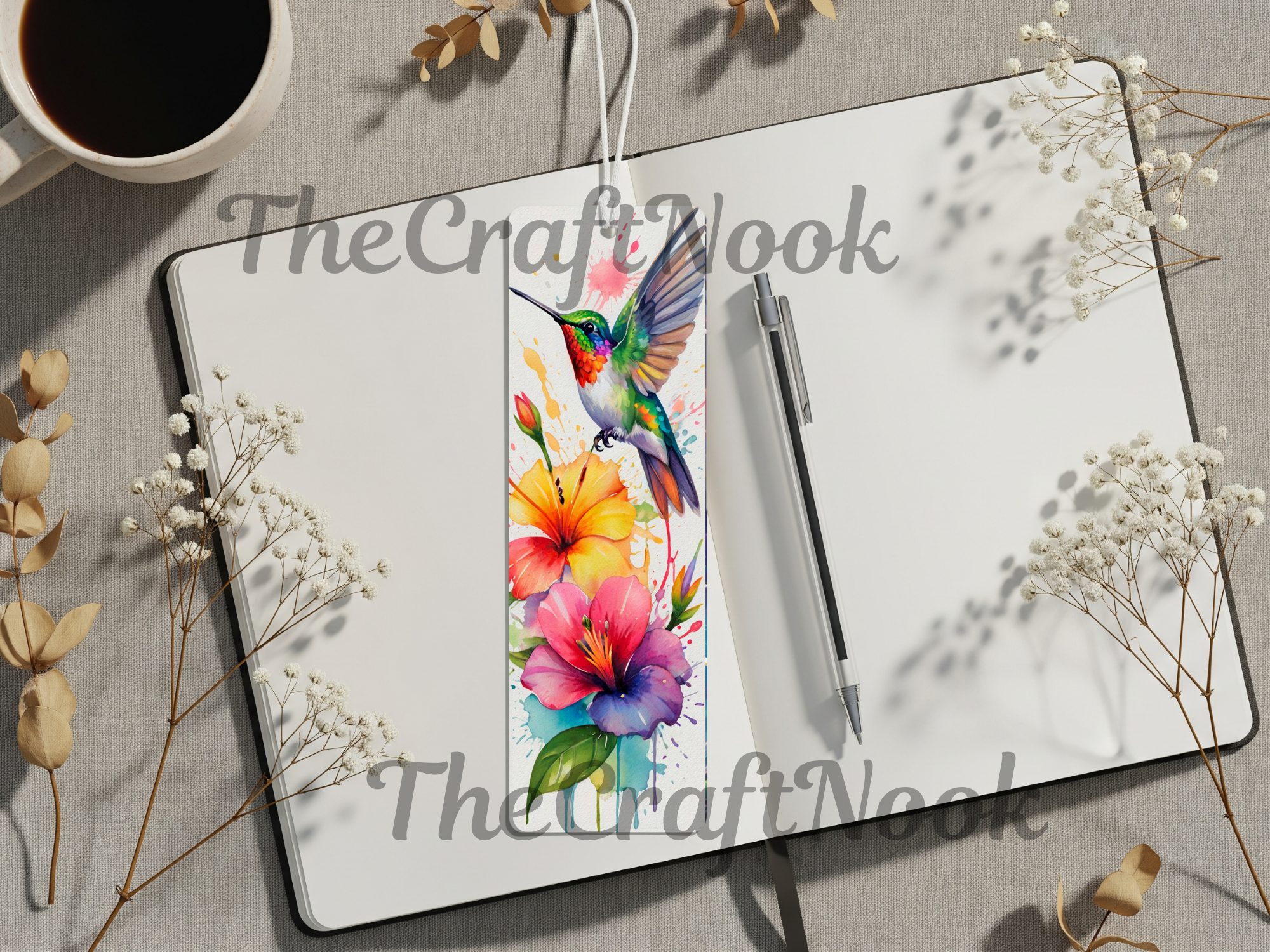 Hummingbird aluminum bookmarks featuring vibrant floral designs, placed on an open notebook with a coffee cup.