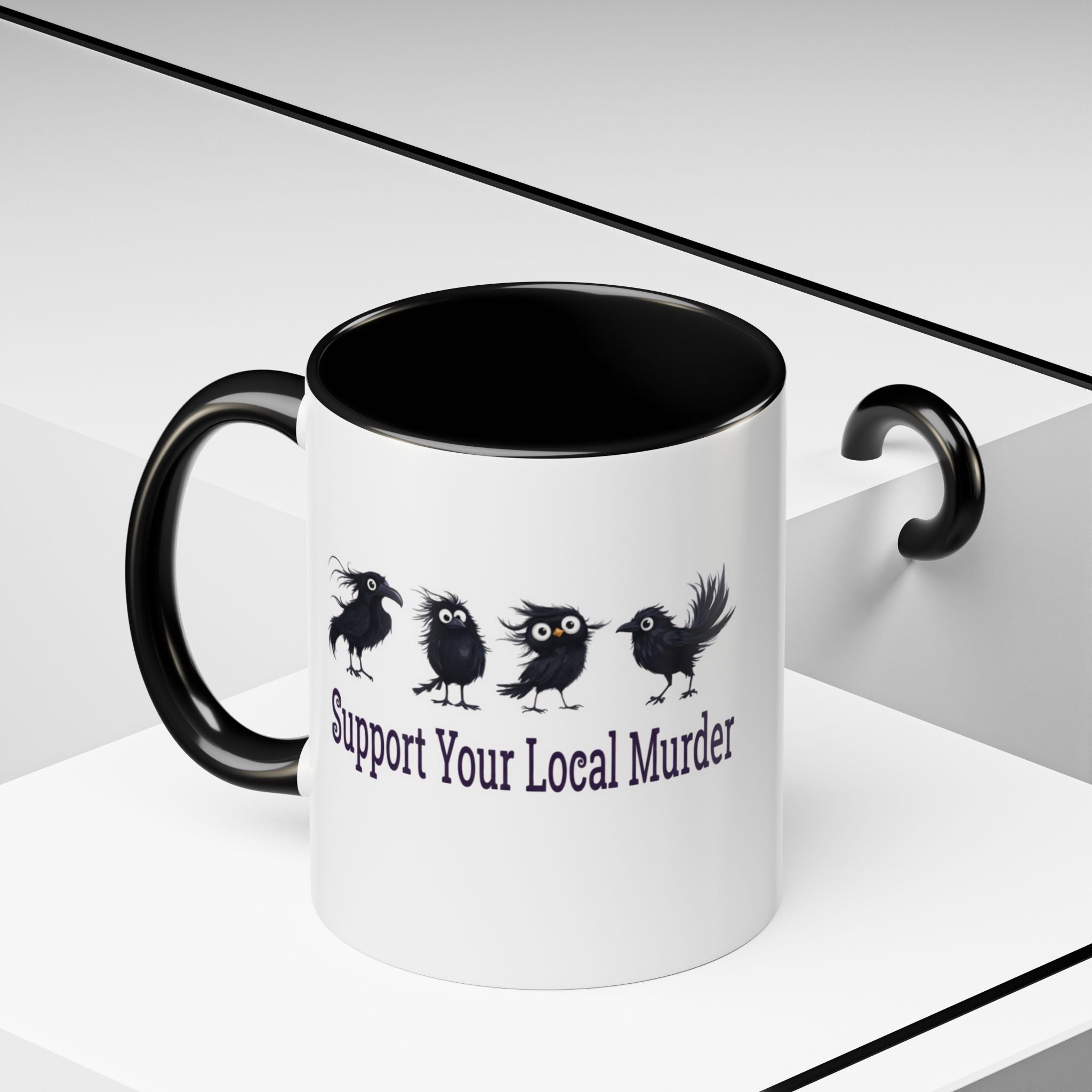 A white ceramic mug with a black handle and black interior, printed with four black birds and the phrase 'Support Your Local Murder' in dark purple text. The mug is shown on a clean white geometric background with a black handle-shaped shadow or prop on the right.