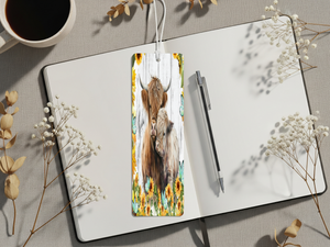 Aluminum highland cow metal bookmarks displayed on a notebook with flowers and a coffee cup.