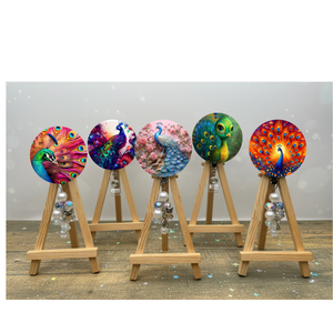 Colorful peacock badge pulls with glitter displayed on easels, showcasing artistic designs and decorative beads.