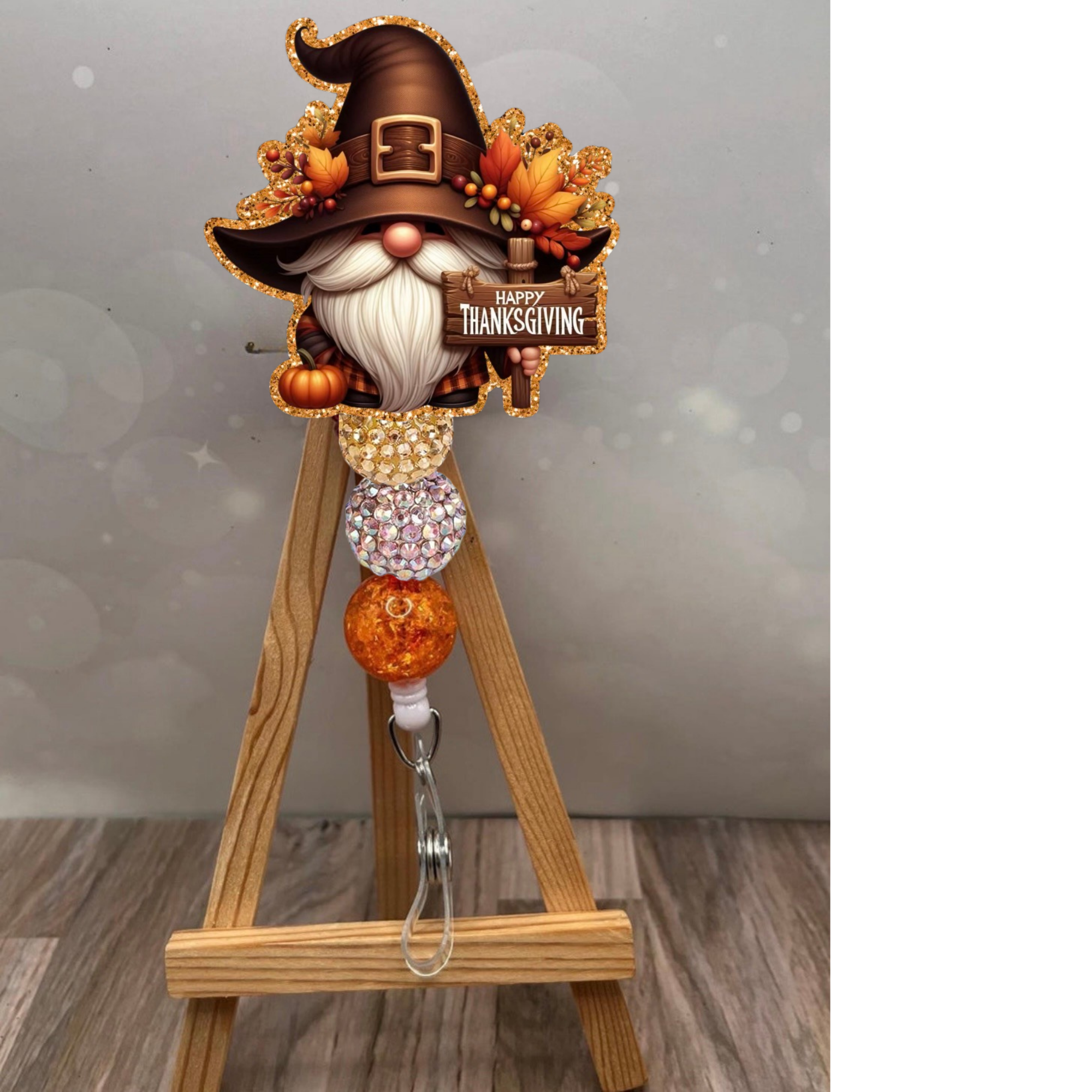 Thanksgiving gnome badge pull featuring a gnome with a brown hat, glitter beads, and a Happy Thanksgiving sign against a glittery background.