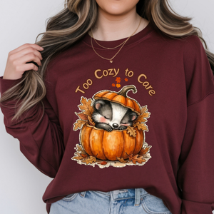 Woman wearing a cozy long sleeve graphic tee featuring a sleeping raccoon in a pumpkin design.