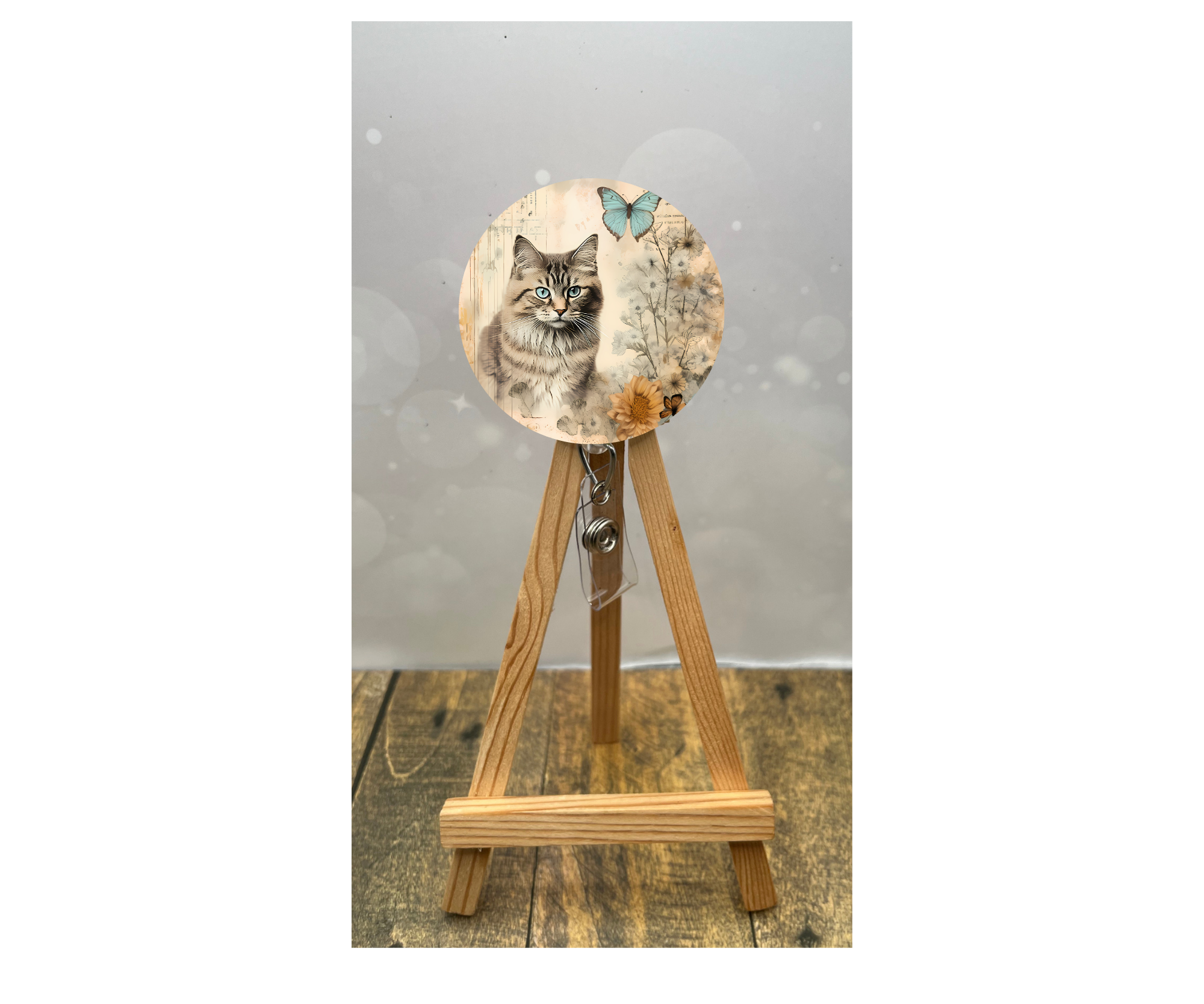 Cat badge pulls for nurses featuring a cute feline design with a butterfly, displayed on a wooden stand.