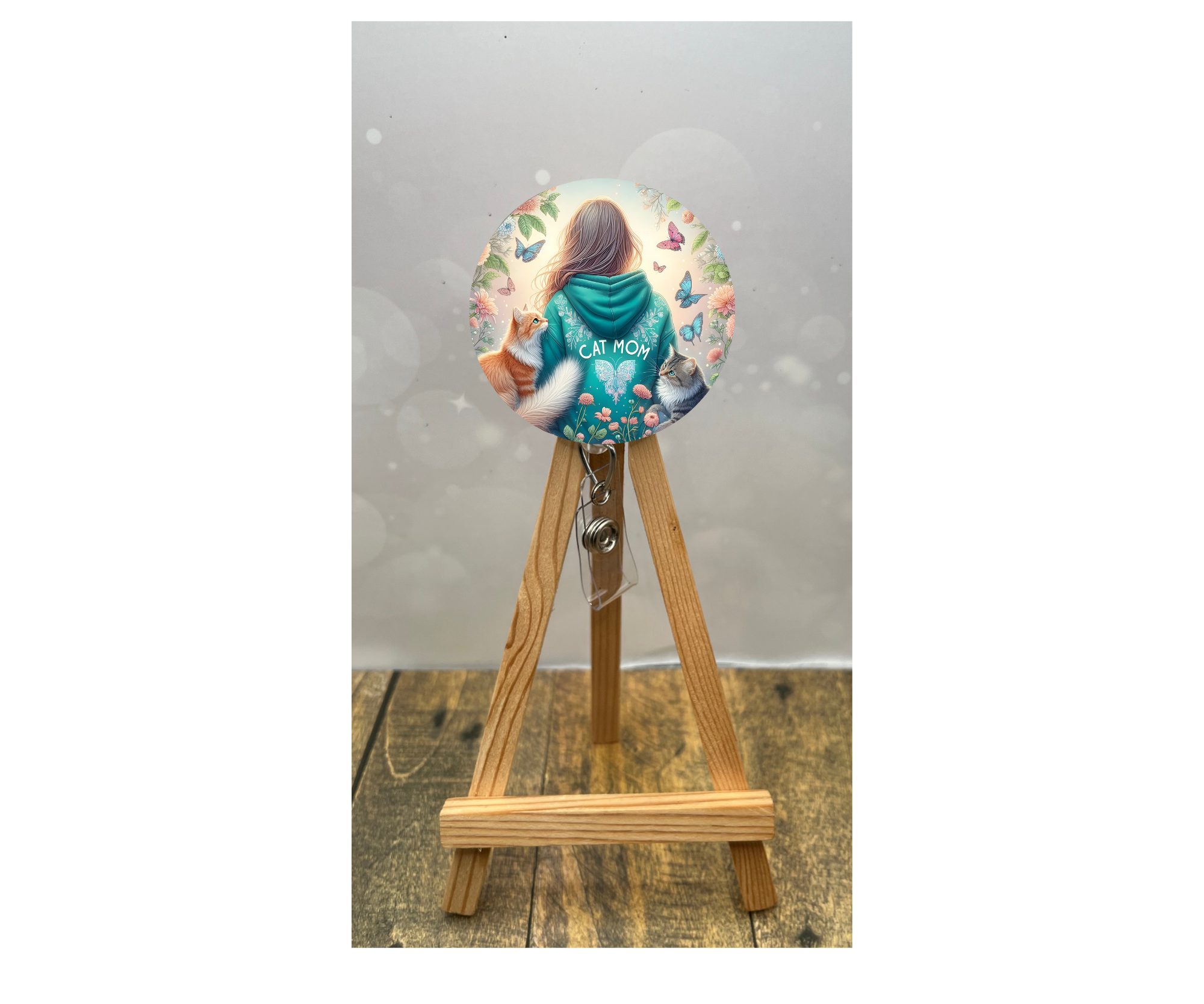 Colorful cat badge pull for nurses featuring a girl in a CAT MOM hoodie, surrounded by flowers and butterflies.