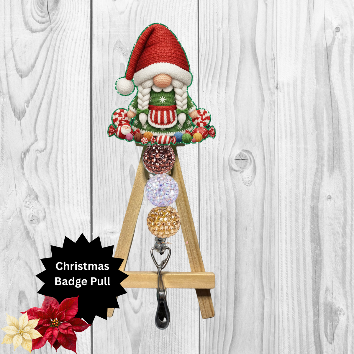 A Christmas-themed wooden A-frame badge pull hook with a gnome figure wearing a red Santa hat and green striped sweater, holding several colorful round badge blanks. The product is shown against a white wood plank background with a black starburst label reading 'Christmas Badge Pull' and small flower graphics in the lower left.