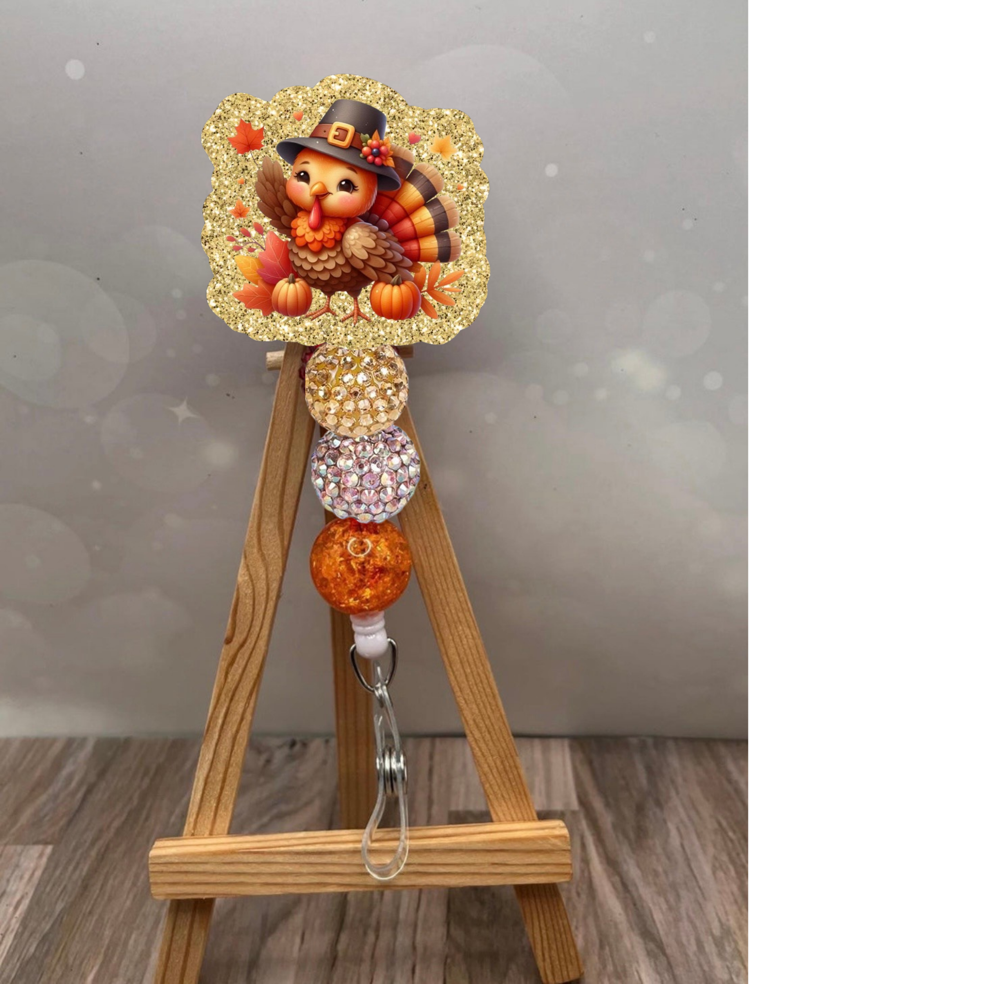 Cute turkey badge reel with glitter background for Thanksgiving featuring colorful beads and adorable turkey design.