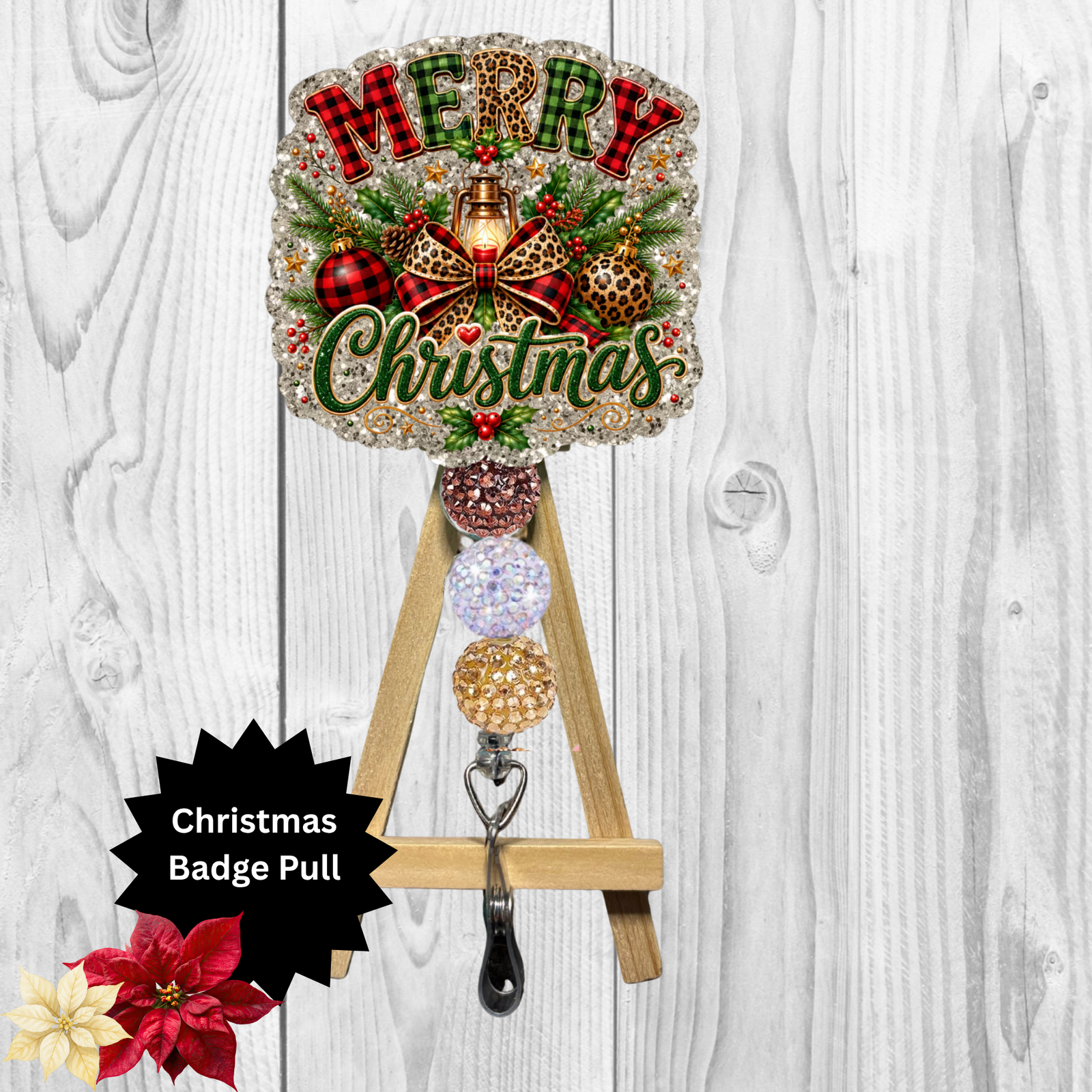 A Christmas-themed badge pull sign with a decorative round top featuring the words “Merry Christmas” and holiday ornaments, mounted on a small wooden A-frame stand. The stand includes four dangling round badge reel cups in different glittery colors and a metal hook at the bottom.