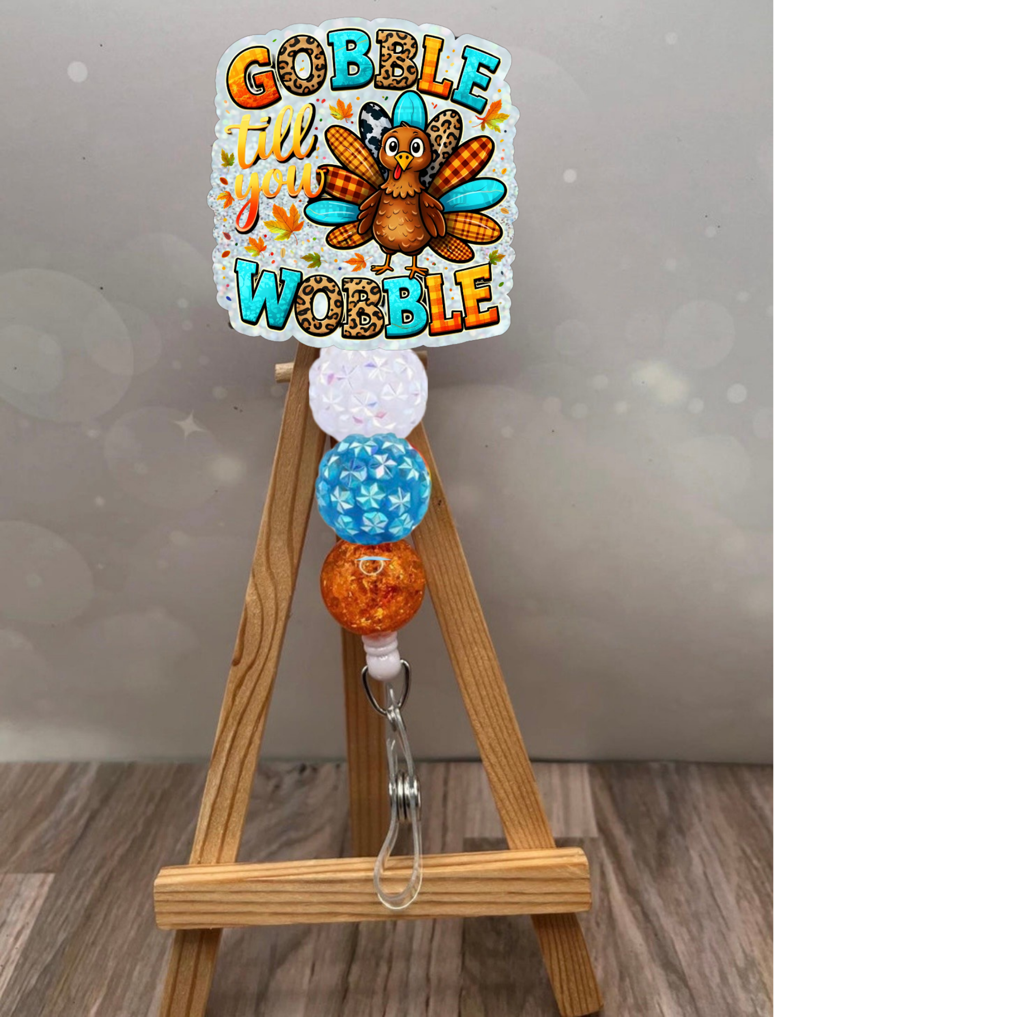 Thanksgiving retractable badge reel featuring a whimsical turkey design and colorful beads on a wooden easel.