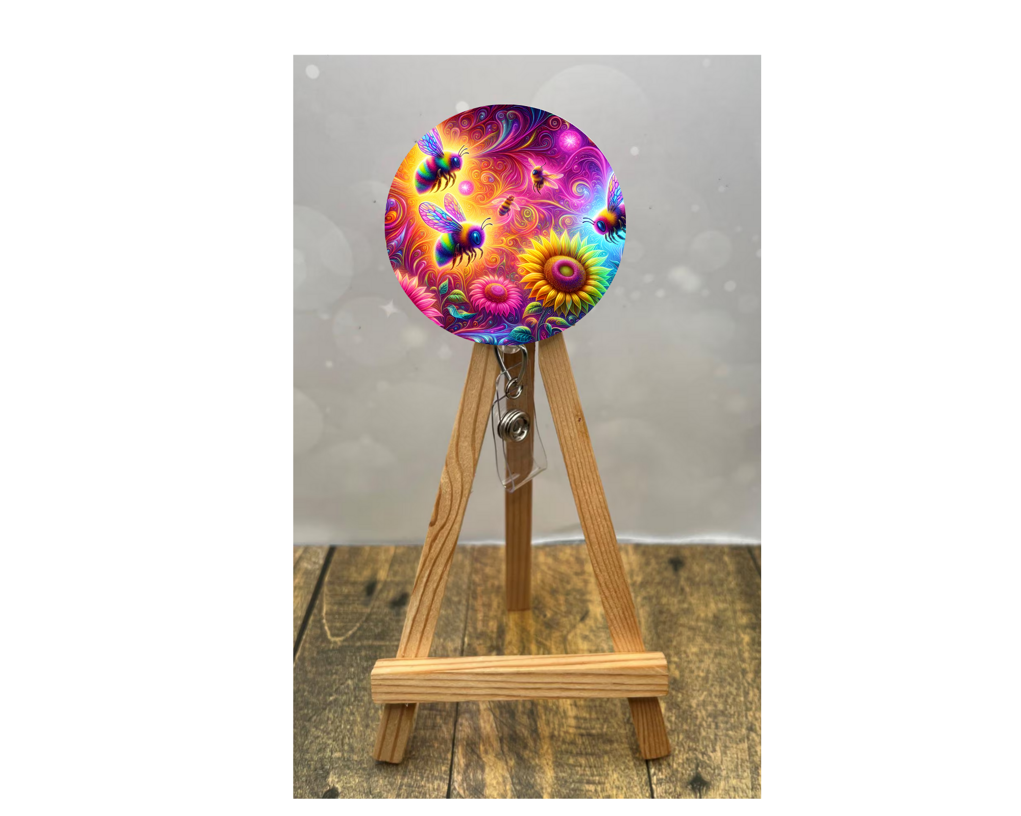 Cute honeybee badge pulls featuring vibrant bee and floral designs on a badge reel displayed on an easel.