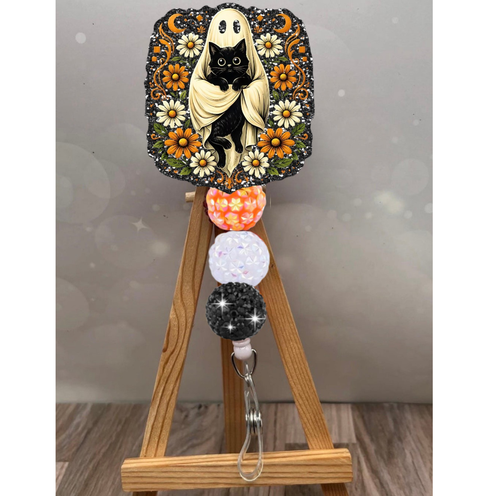 Ghost Cat Badge Reel with black glitter background, cute Halloween badge reel for cat lovers, adorned with flowers.