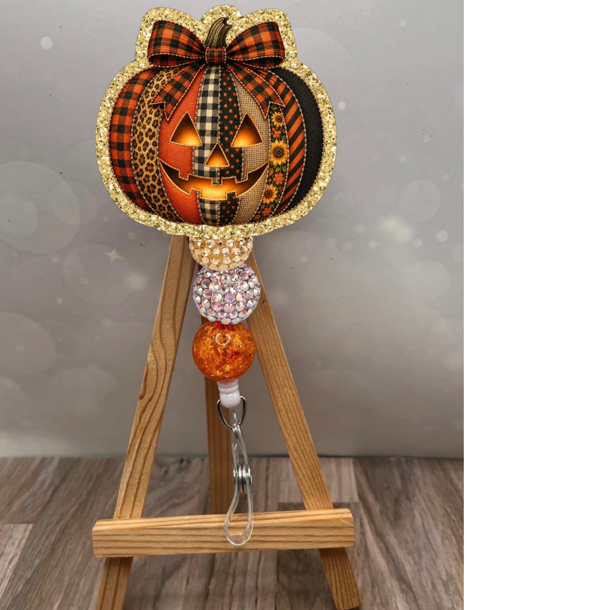 Patchwork Jack-O-Lantern Badge Reel with glitter background and colorful beaded strap for Halloween.