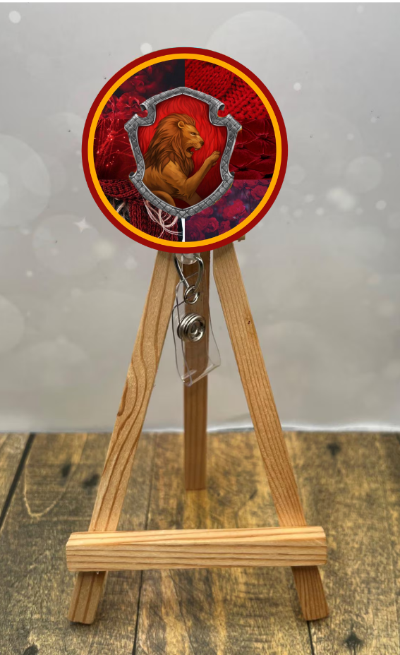 Gryffindor badge pull with glitter displayed on an easel, featuring a lion design and vibrant red background.