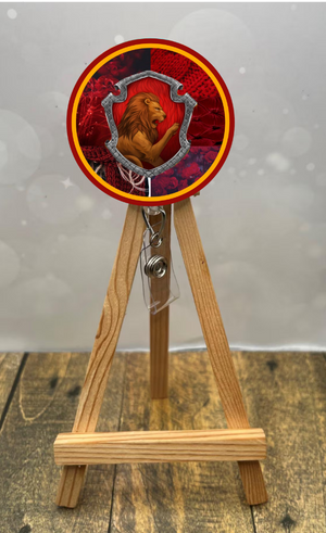 Gryffindor badge pull with glitter displayed on an easel, featuring a lion design and vibrant red background.