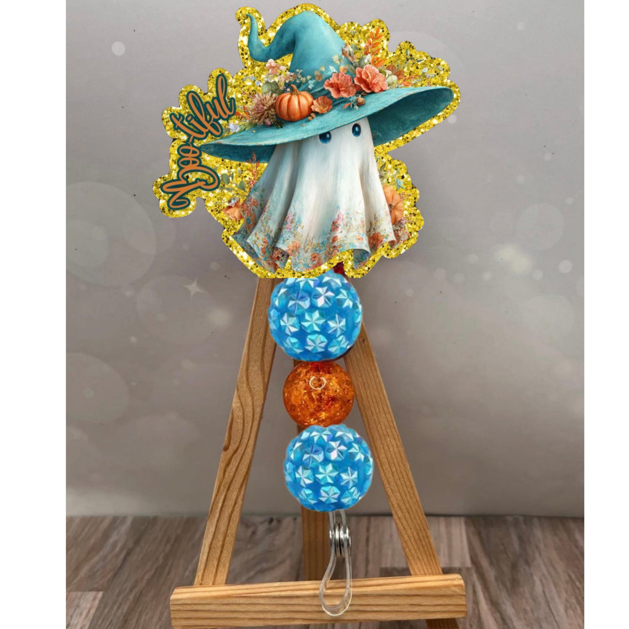 Halloween badge reel featuring a ghost with a hat, decorated with floral accents and colorful beads.
