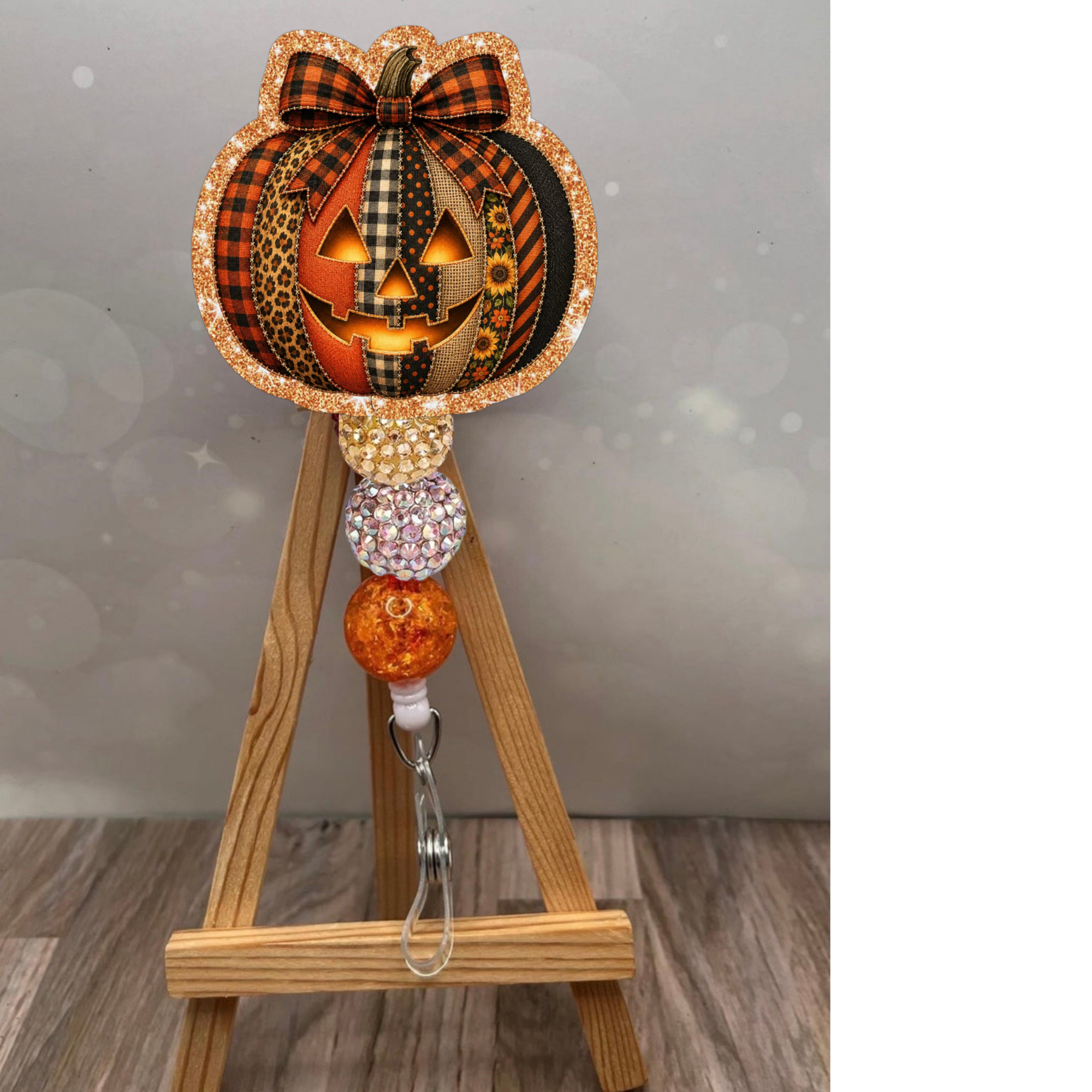 Patchwork jack-o-lantern badge reel with glitter background and colorful beads on an easel.
