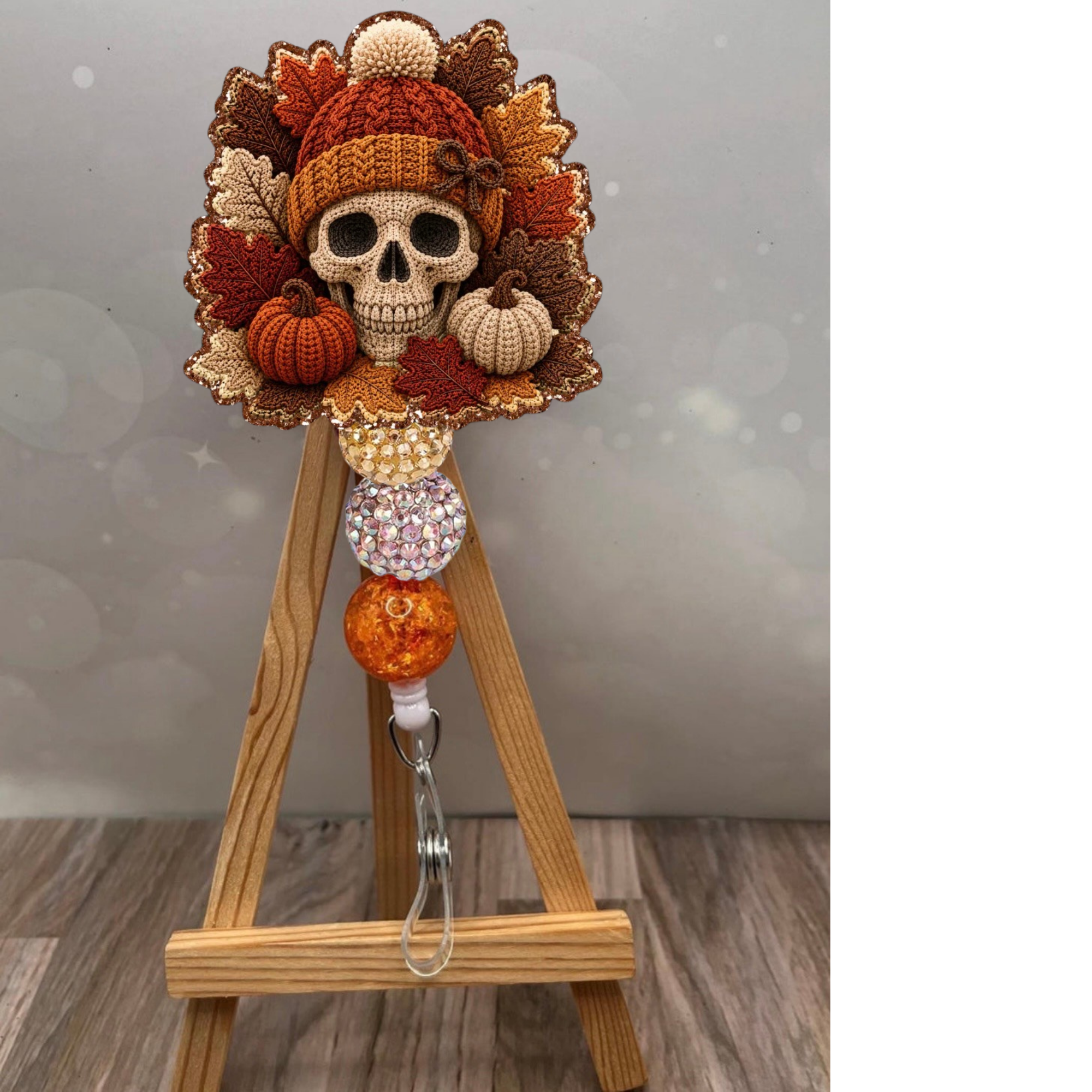 Fall Crochet Skull Badge Pull showcasing a colorful skull design with autumn leaves and pumpkins on a wooden stand.
