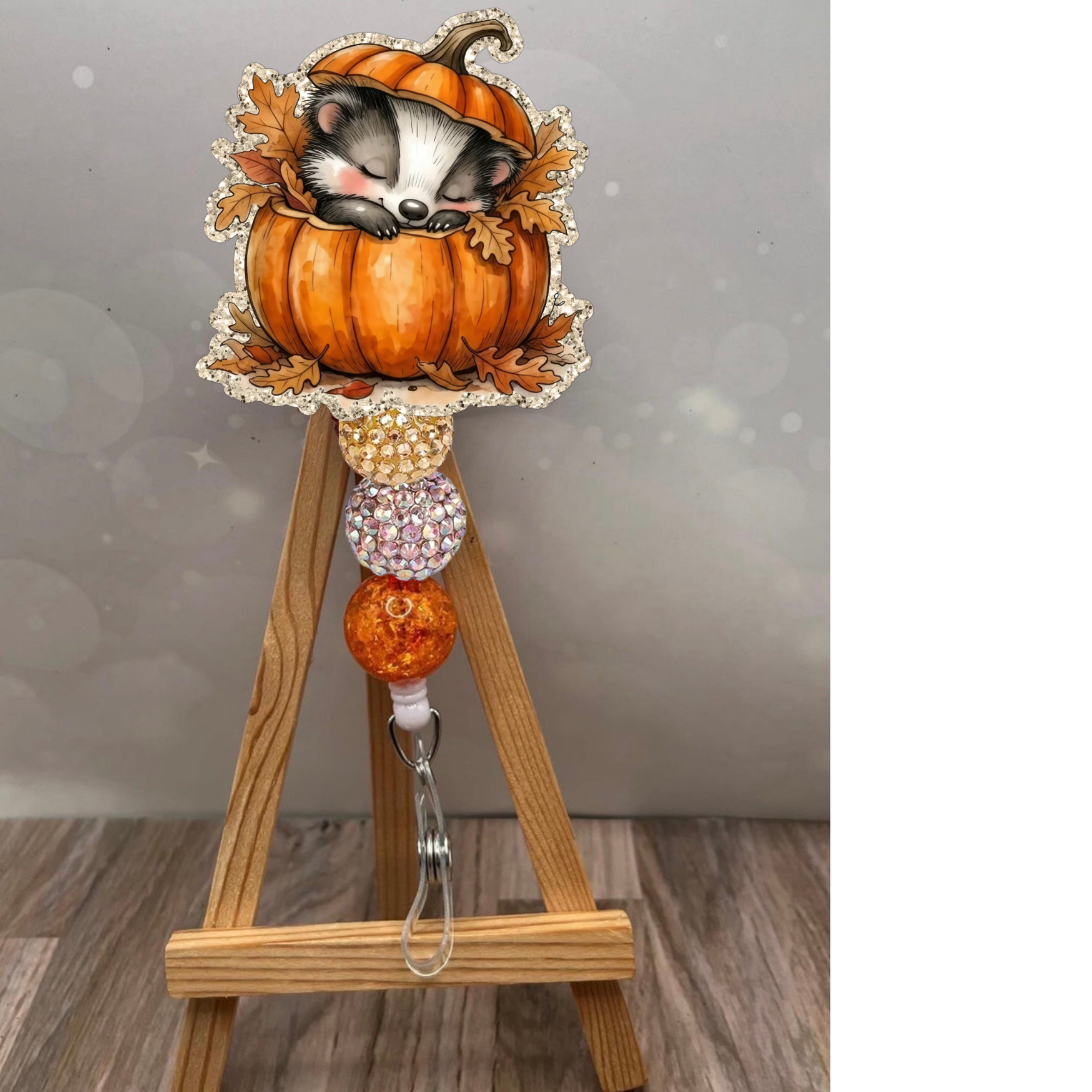 Cozy badger badge reel featuring a sleepy badger in a pumpkin with colorful beads and an earthy background.