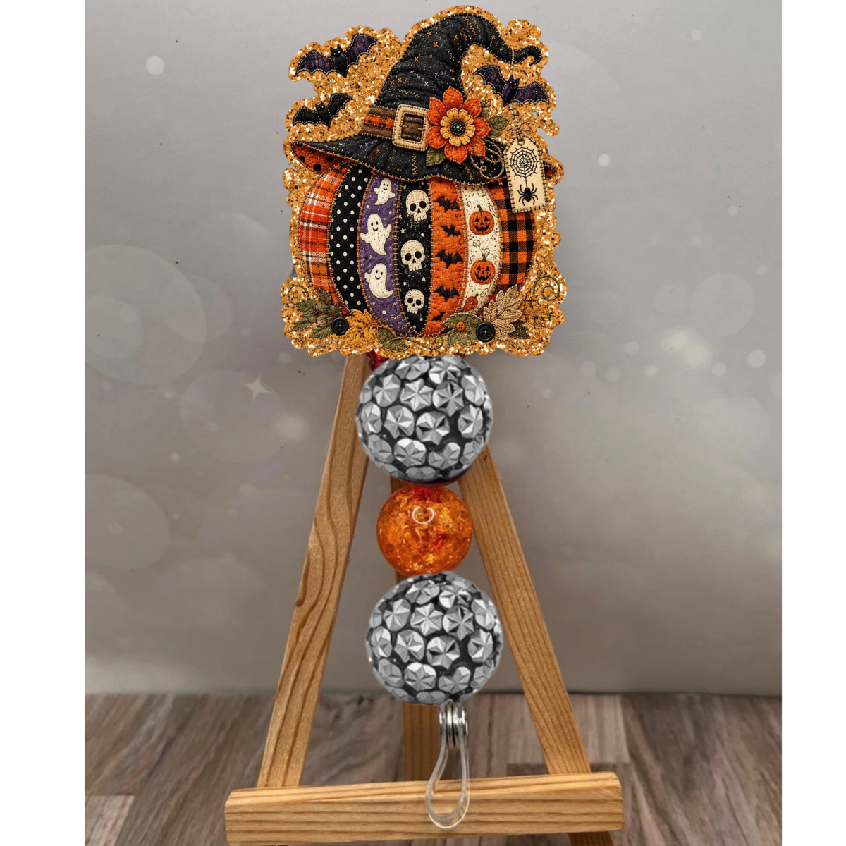 Colorful patchwork pumpkin badge reel with orange glitter background, perfect for fall enthusiasts.