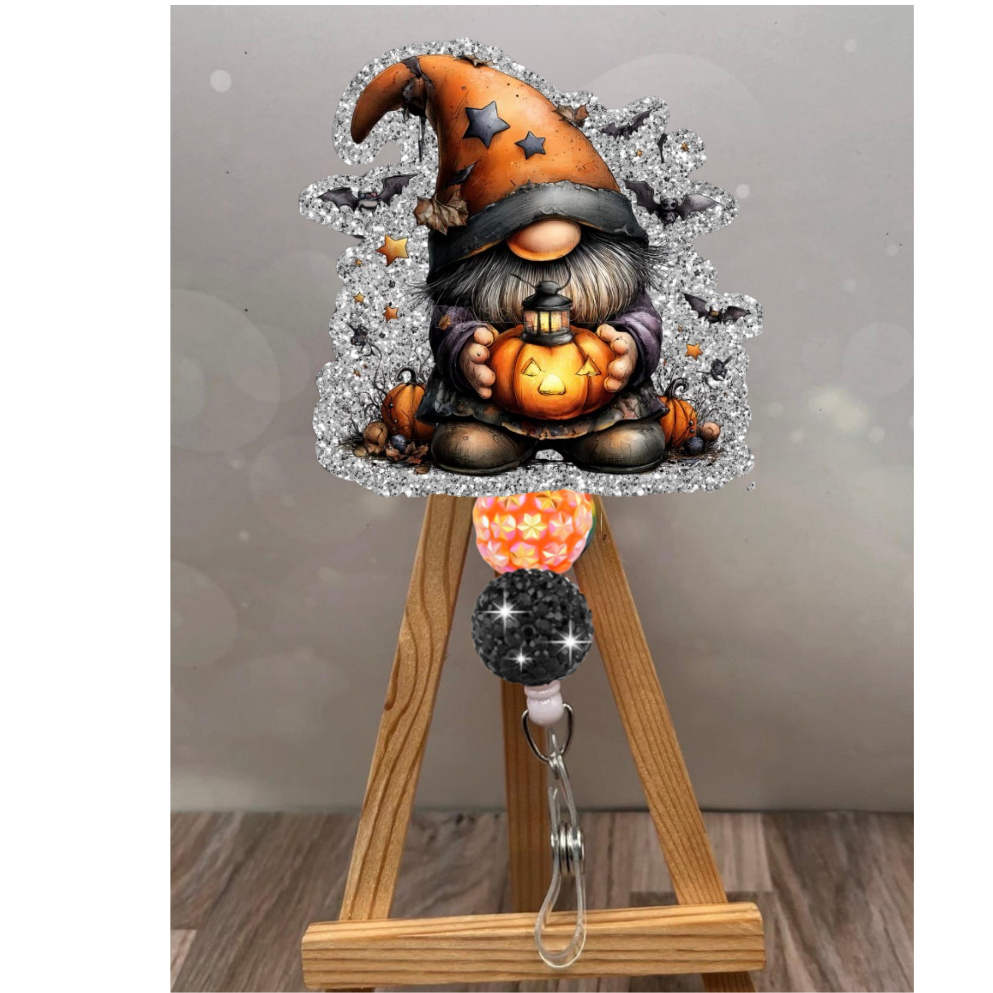 Halloween badge reel gnome with glitter background holding a pumpkin, attached to a colorful retractable badge holder.