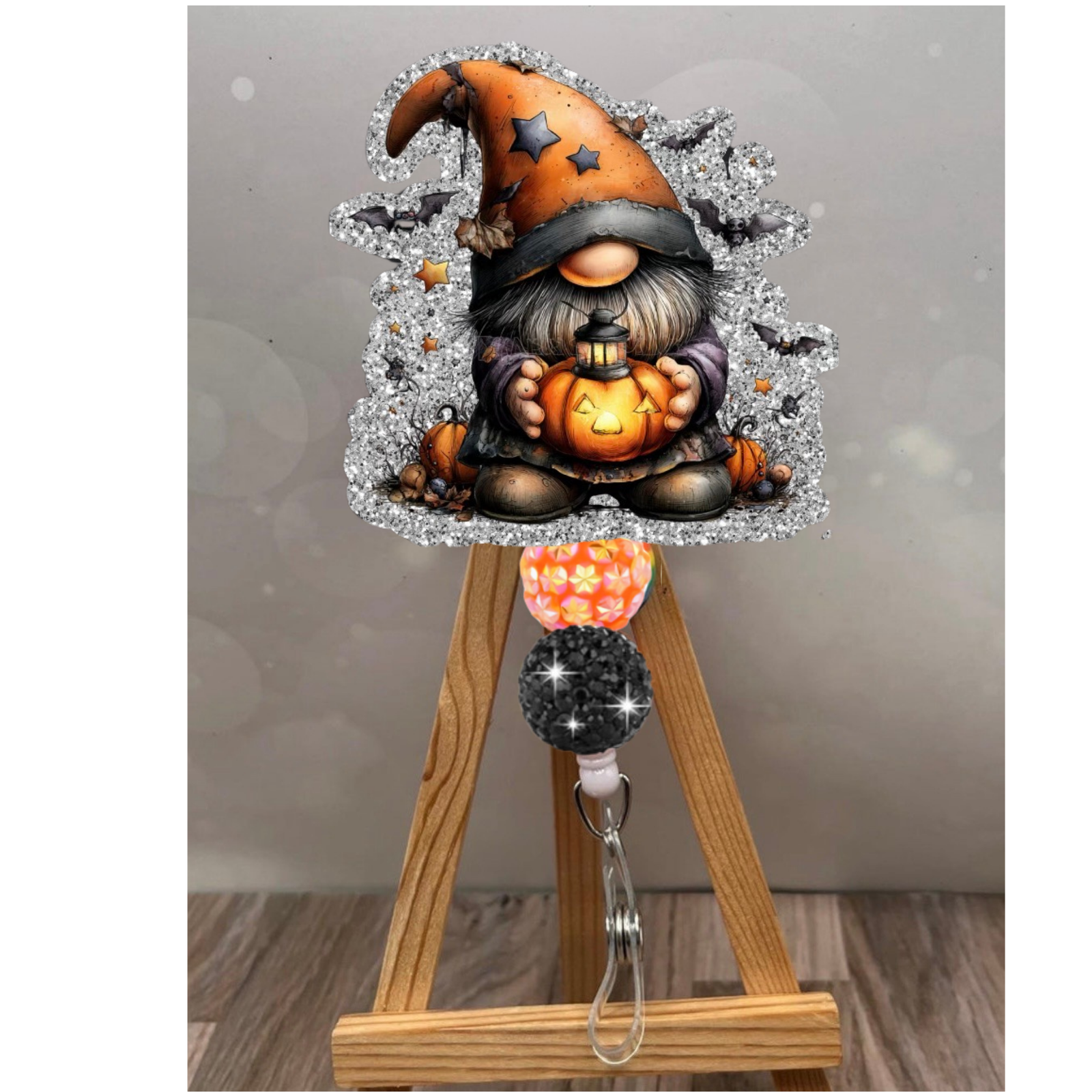 Halloween badge reel gnome with glitter background holding a pumpkin, attached to a colorful retractable badge holder.
