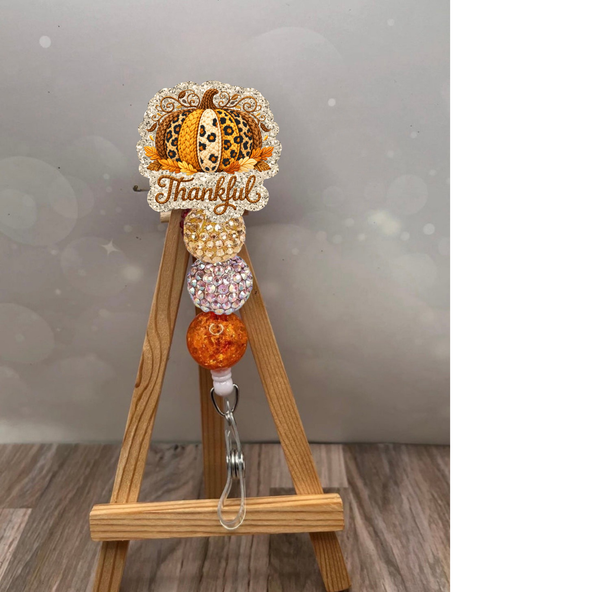 Thankful Crochet Pumpkin Badge Reel featuring glittery orange and pink beads, perfect for showing fall spirit at work.
