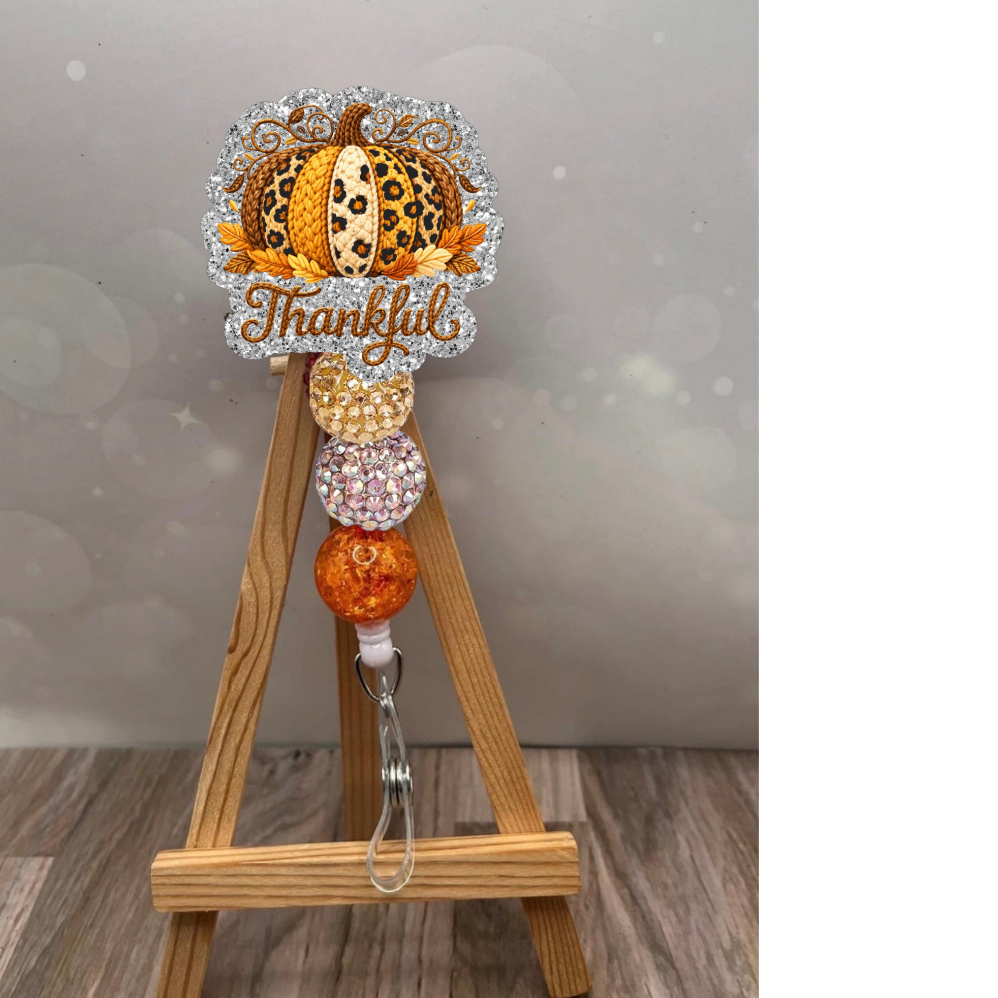 Thankful Crochet Pumpkin Badge Reel with glitter background and autumn colors, perfect for fall-themed work accessories.