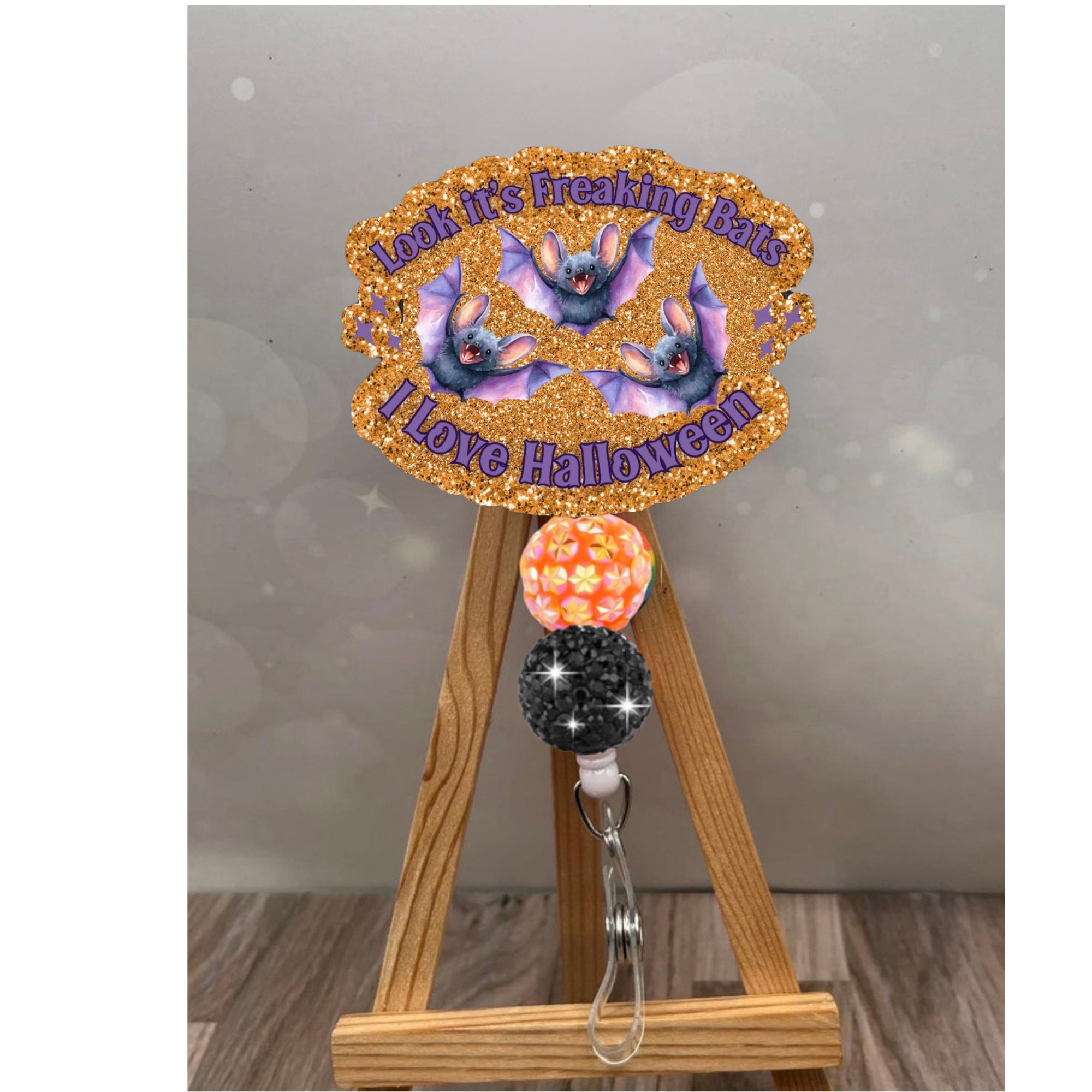 Funny Halloween badge pull featuring glittery orange background and bat design, perfect for Halloween enthusiasts.