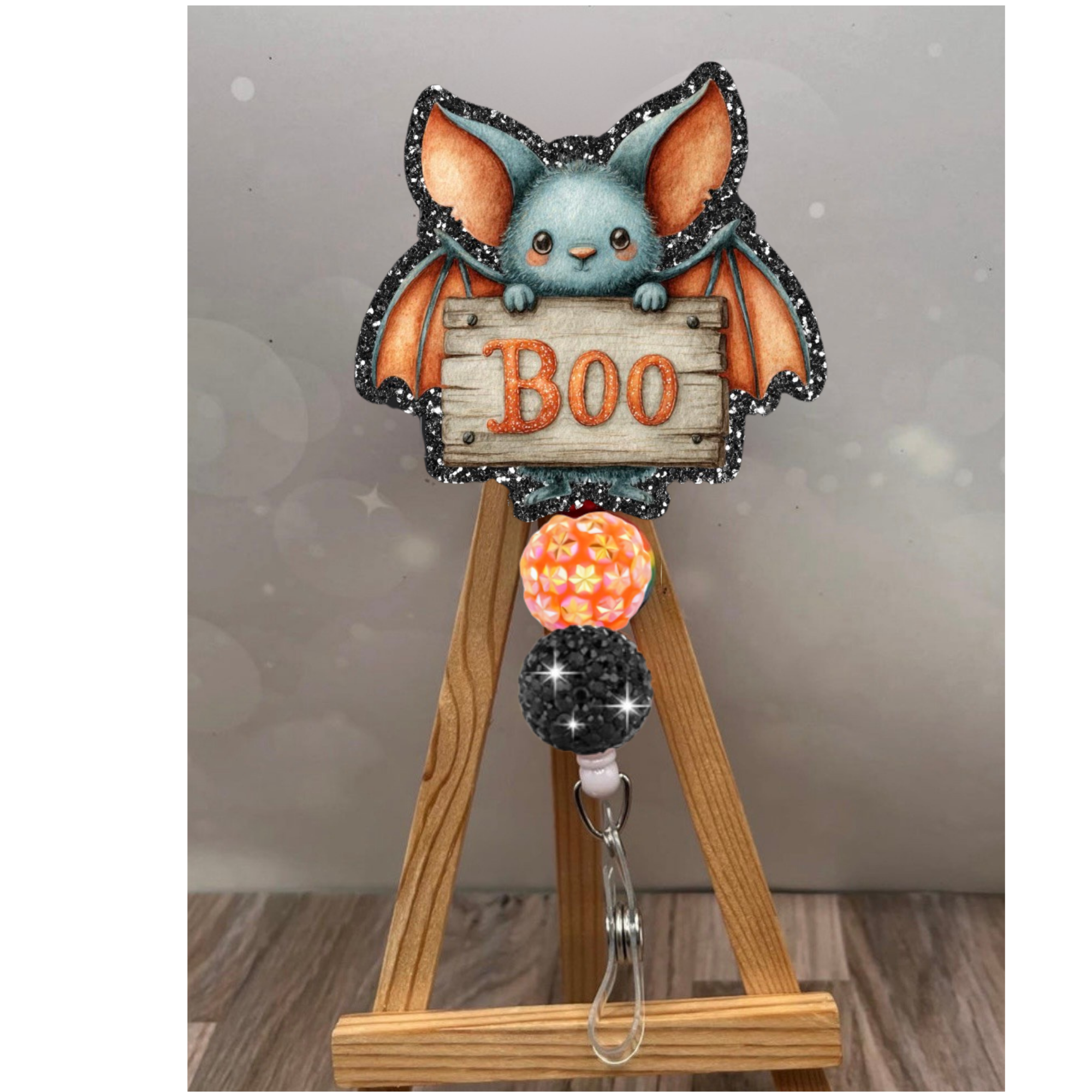 Retractable Halloween badge reel featuring a glittery boo bat design with orange accents and bead charm.