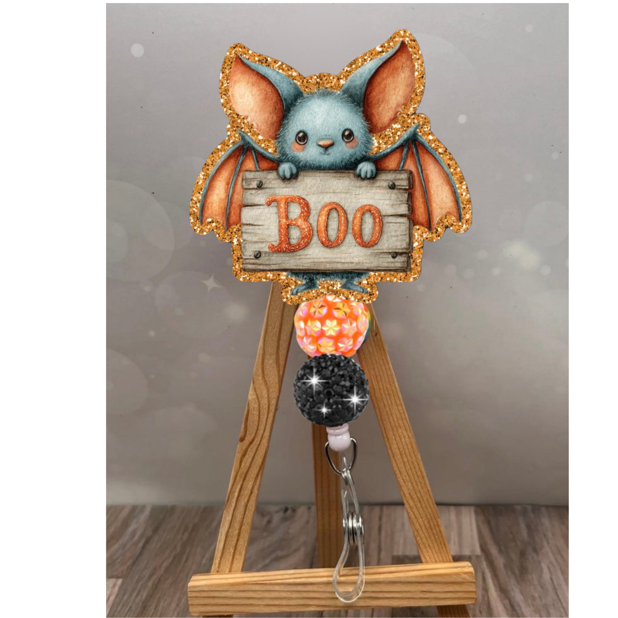 Boo Bat Badge Pull with glittering orange background, a cute bat design, and retractable Halloween badge reel.