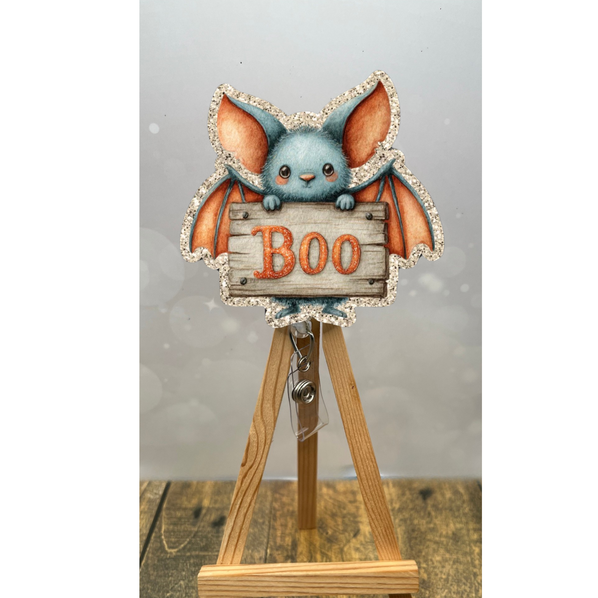 Boo Bat Badge Pull with glitter background, featuring a cute bat holding a 'Boo' sign, perfect Halloween badge reel.