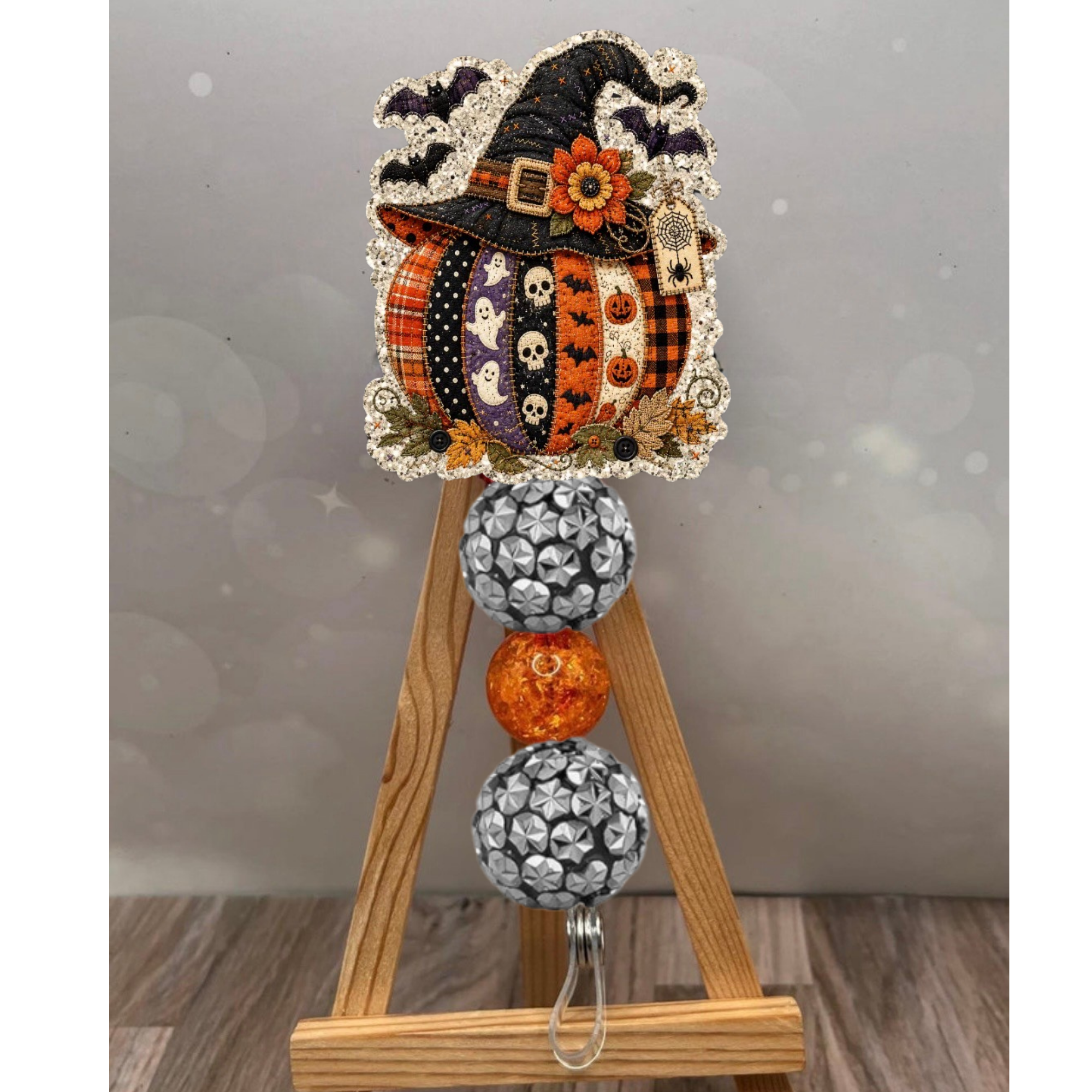 Patchwork pumpkin badge reel featuring a whimsical design with glitter background and sturdy clip for fall-themed attire.