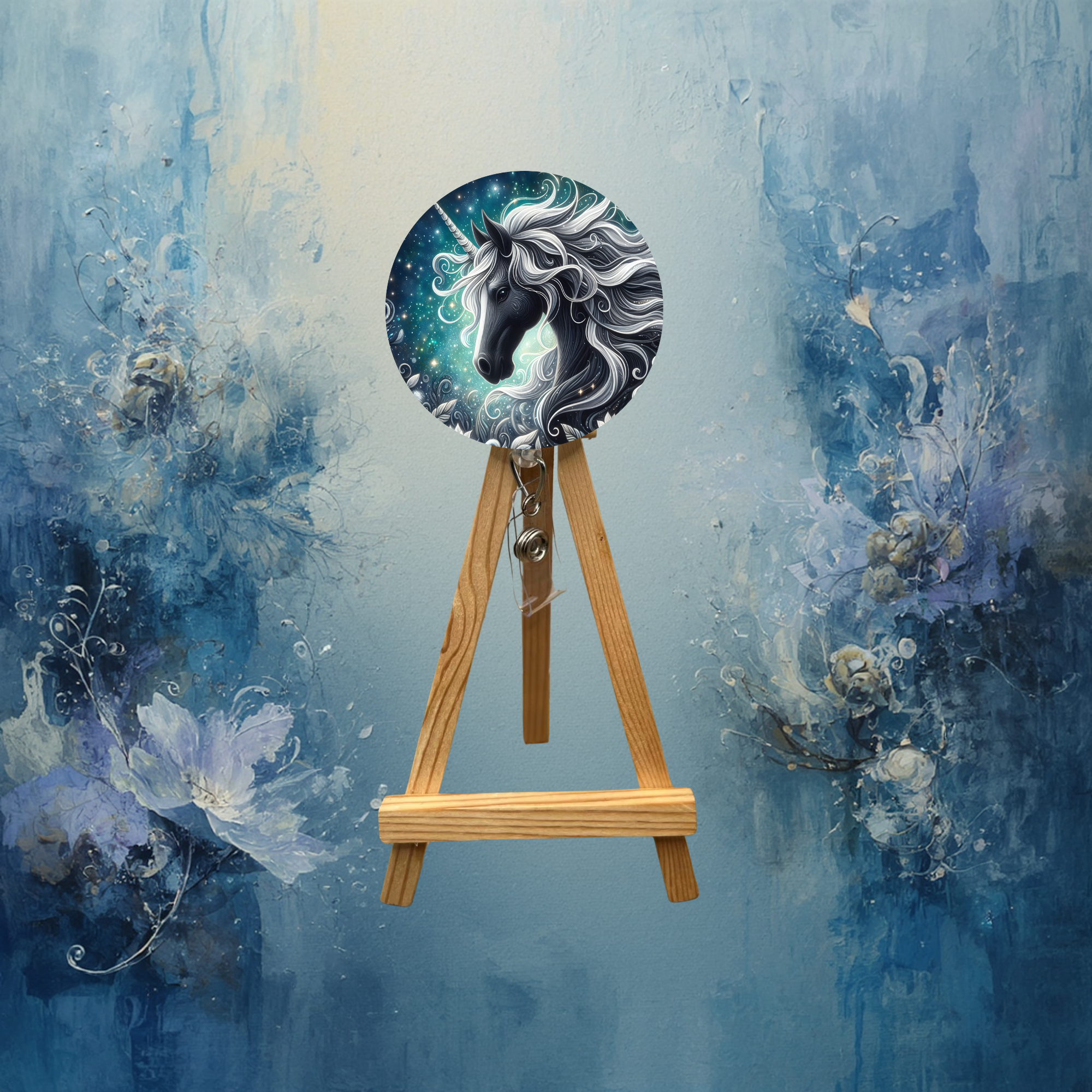Unicorn badge pulls with glitter displayed on a wooden easel against a blue artistic background.