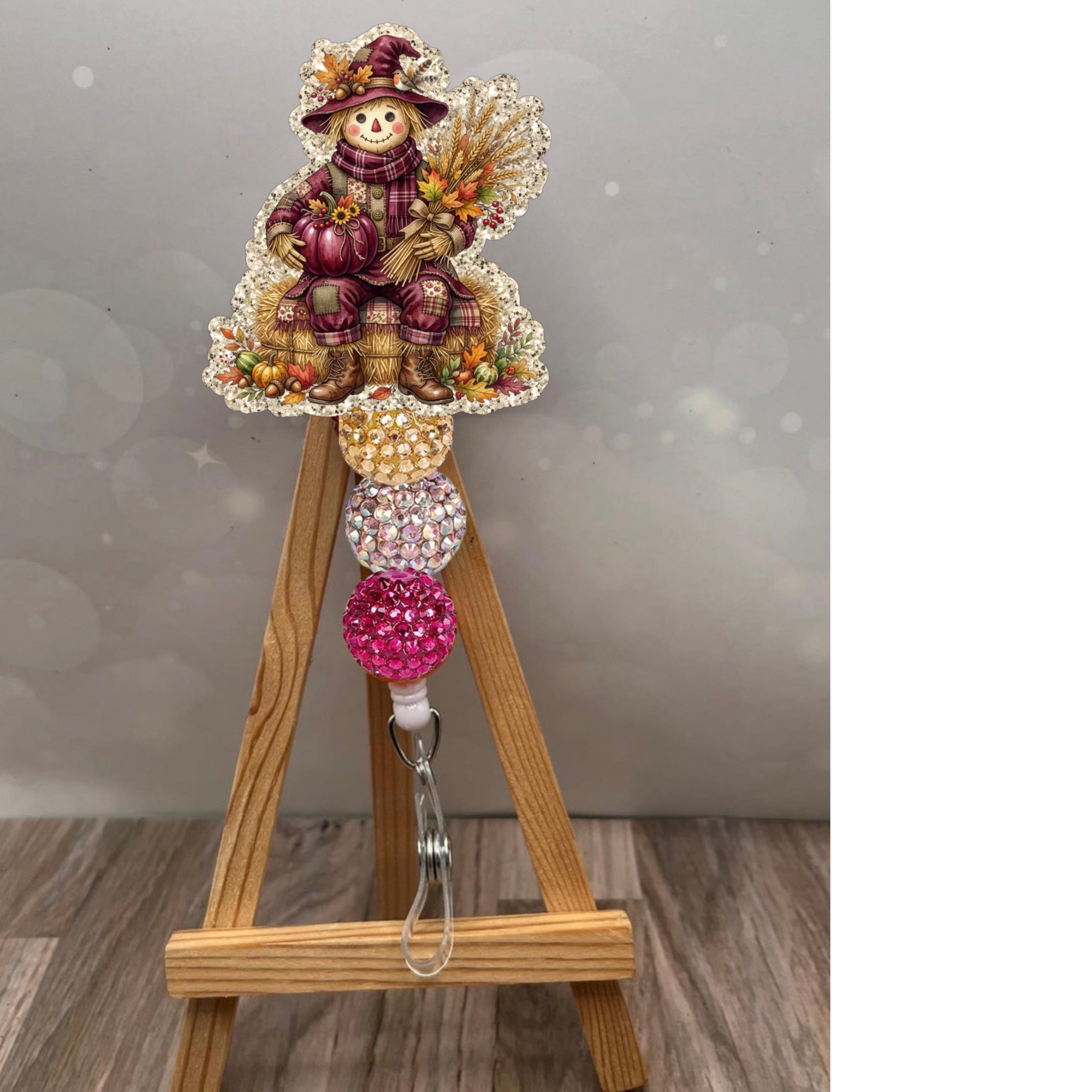 Scarecrow badge pull featuring a glittery background with a charming scarecrow design, perfect for fall-themed accessories.