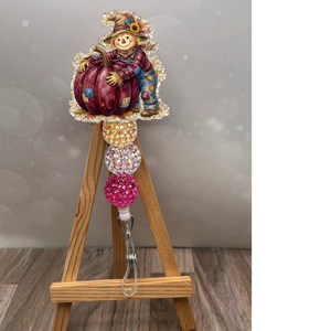 Scarecrow badge reel with pumpkin featuring glitter background and fall colors, perfect for work and seasonal flair.