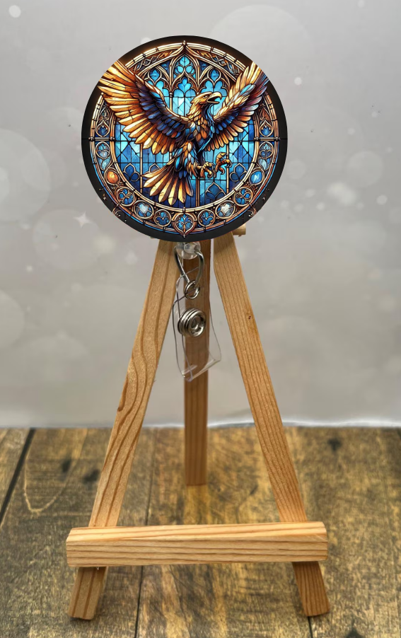 Eagle House badge pull with shimmer glitter displayed on a wooden easel showcasing vibrant eagle design.