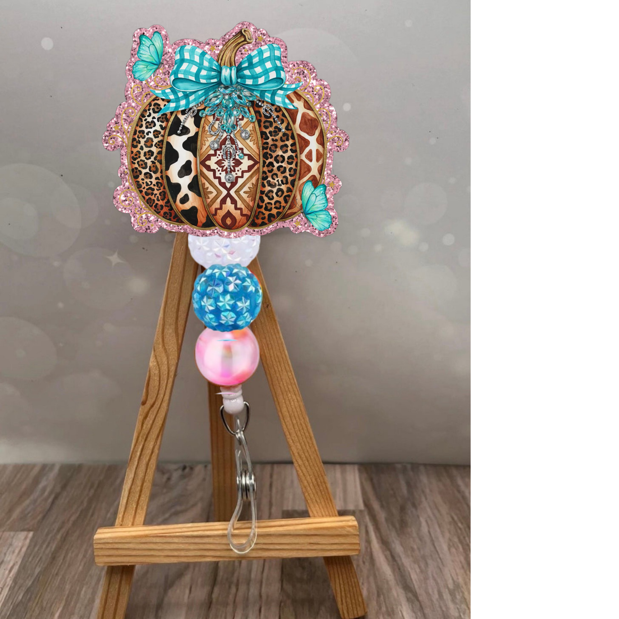 Boho pumpkin badge reel featuring a colorful patchwork pumpkin, bold patterns, teal bow, and glitter background.