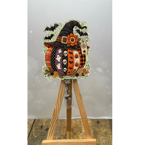 Patchwork pumpkin badge reel with glitter background and whimsical Halloween design on display.