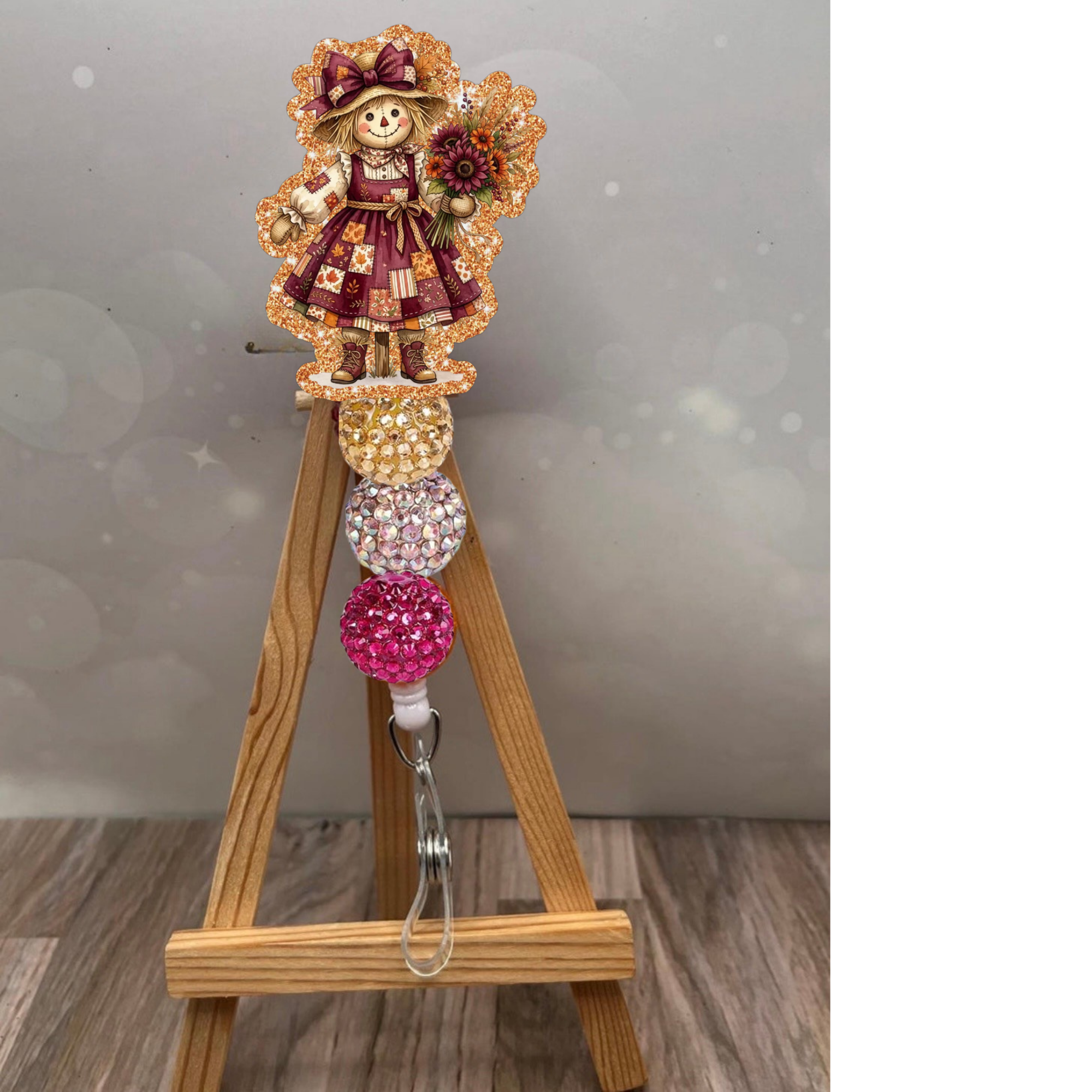 Girl scarecrow retractable badge reel with glitter background in orange, showcasing a charming scarecrow design.