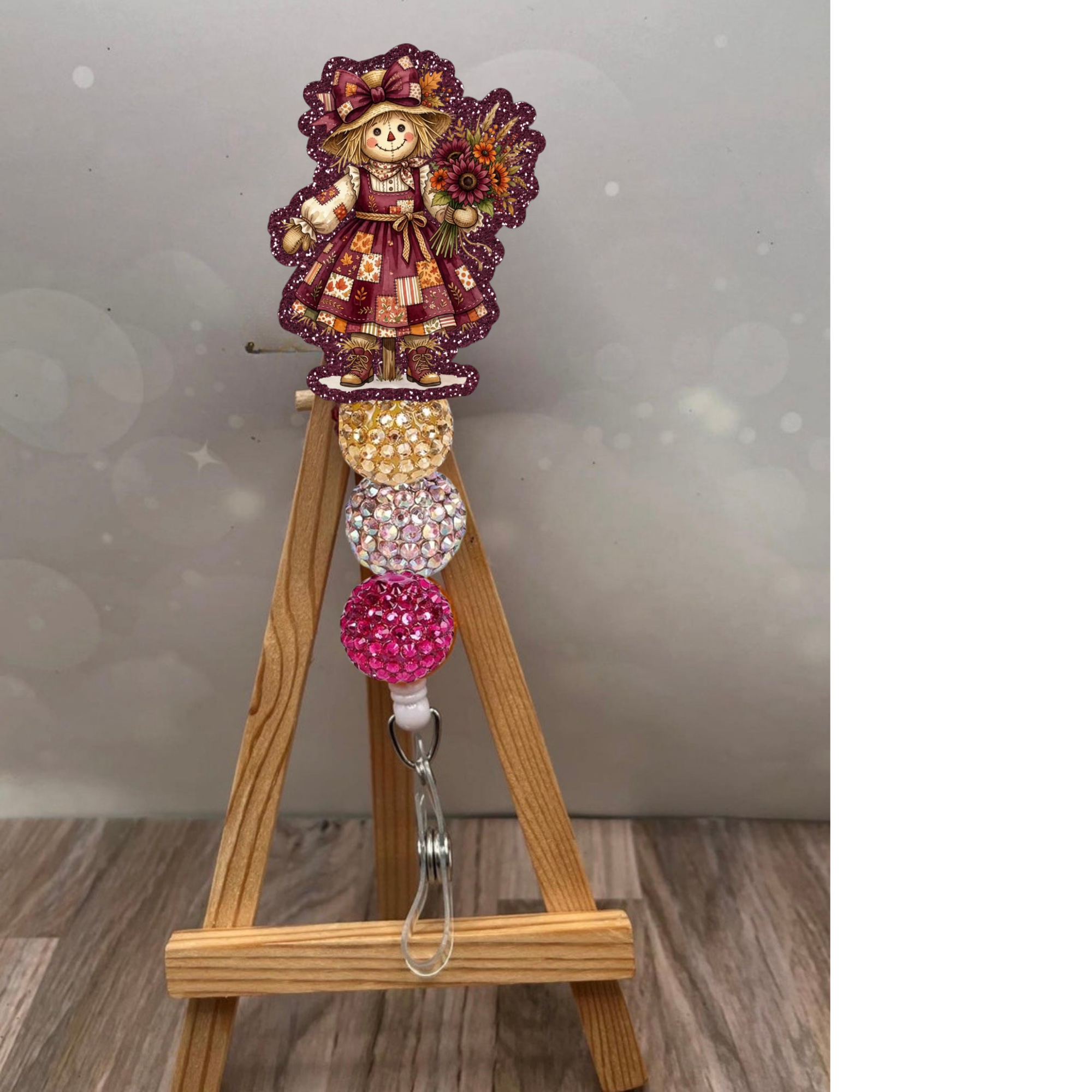 Cute girl scarecrow retractable badge reel on display with glittery plum background, perfect for nurses and teachers.