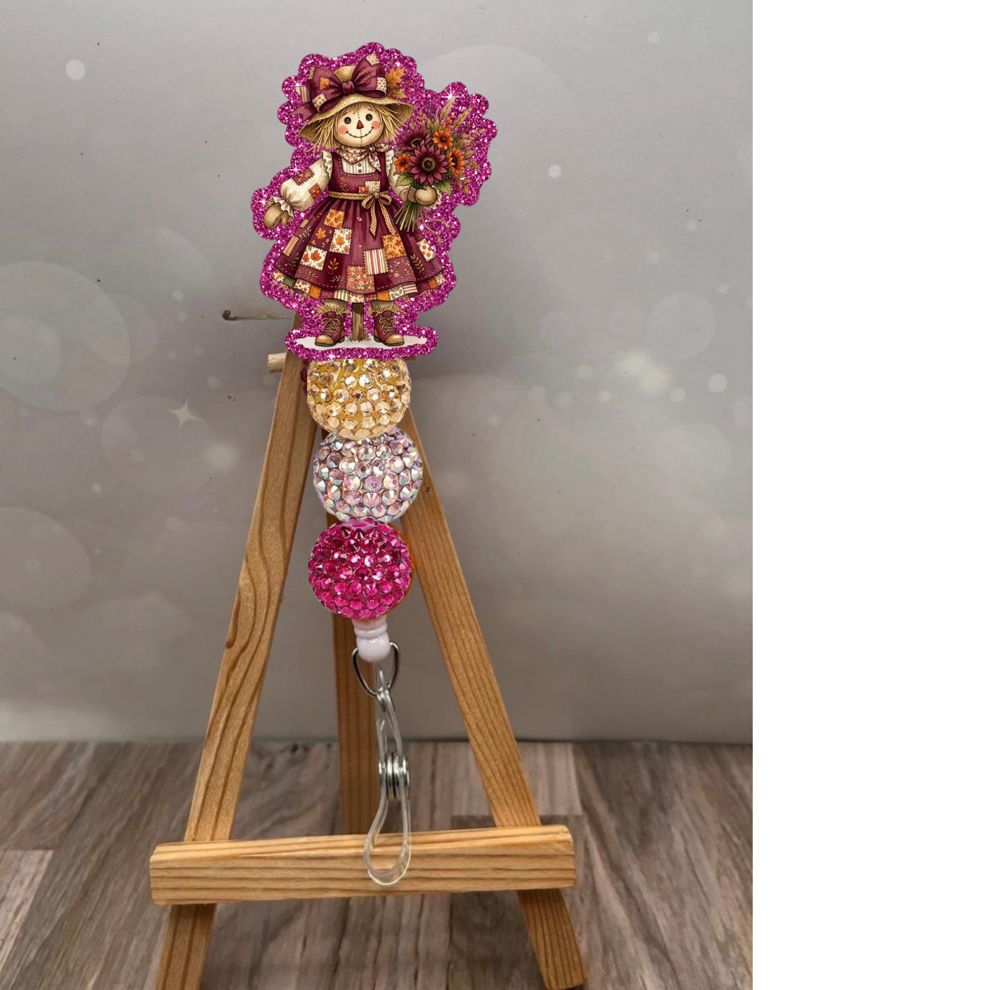Girl scarecrow retractable badge reel featuring a glittery pink design and colorful beaded accents on a wooden easel.