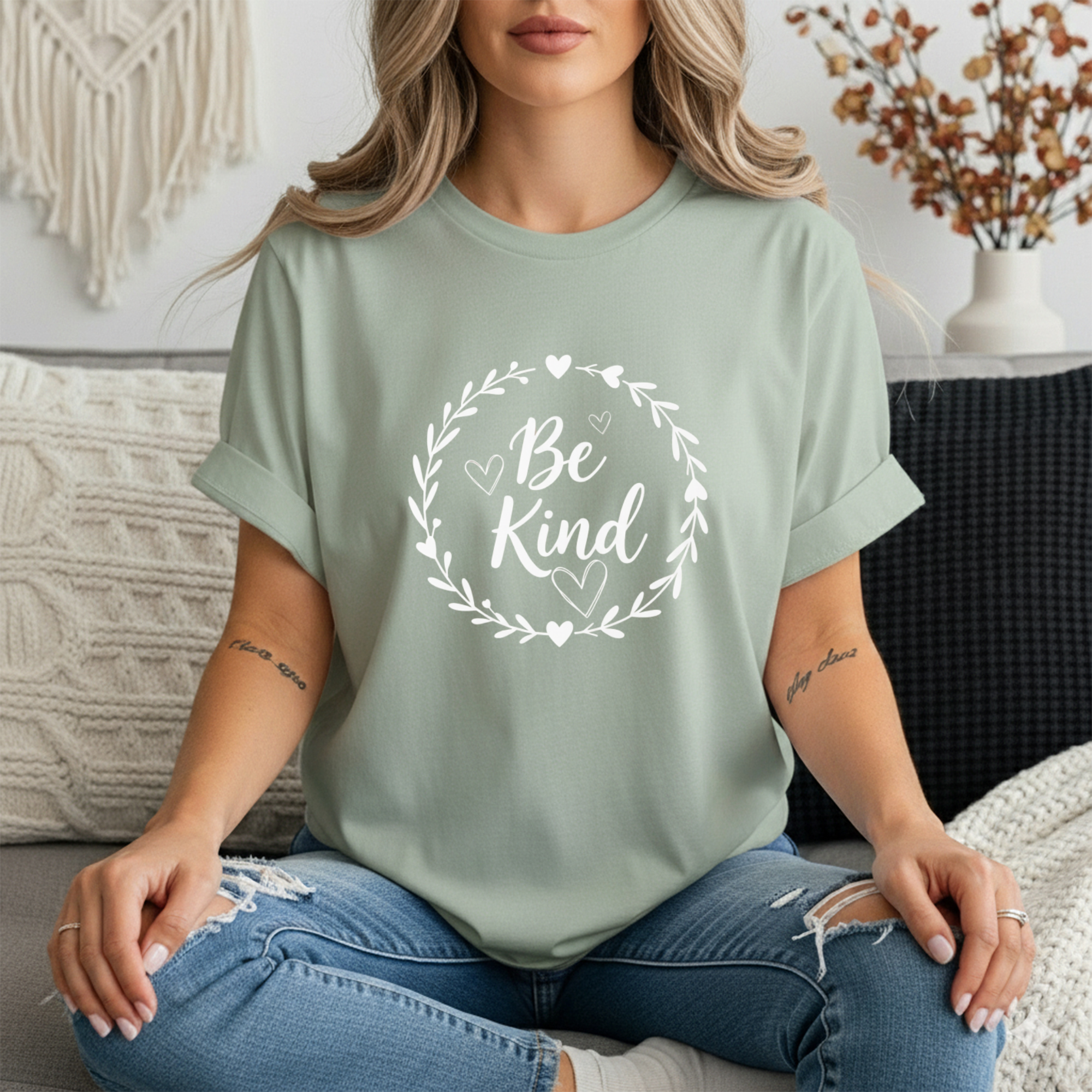 Be Kind Graphic Tee showcased on a model sitting, displaying a message of kindness with a floral design.