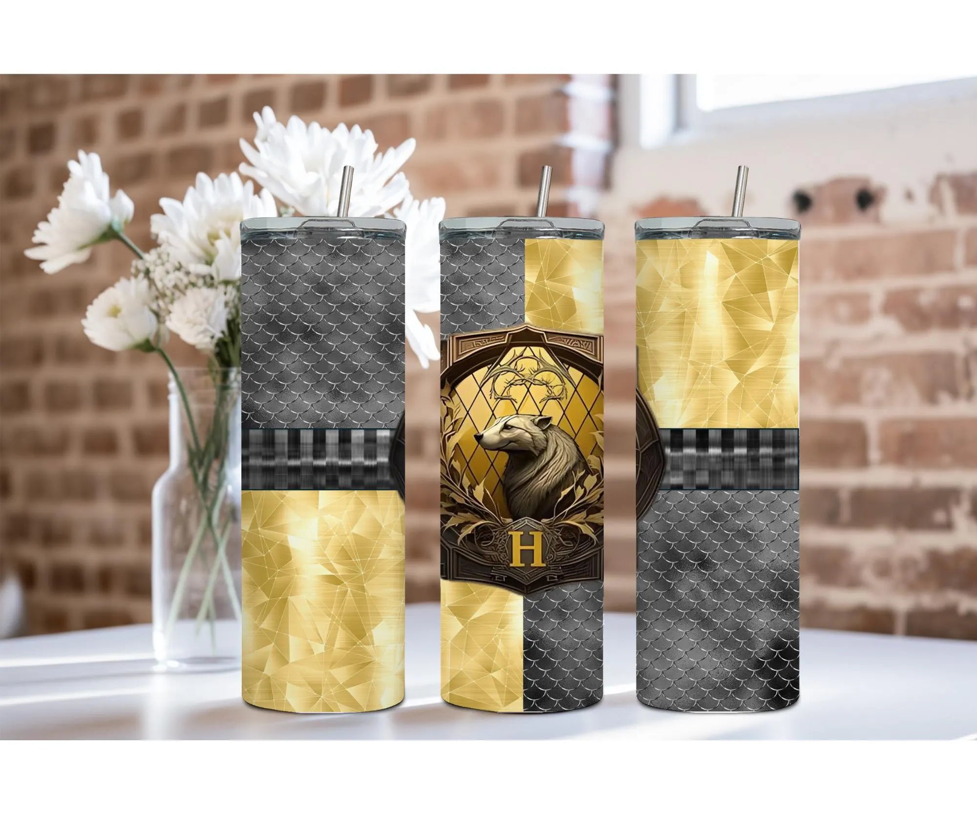 Badger House Pride stainless steel tumblers in gold and black design displayed next to a vase of flowers.