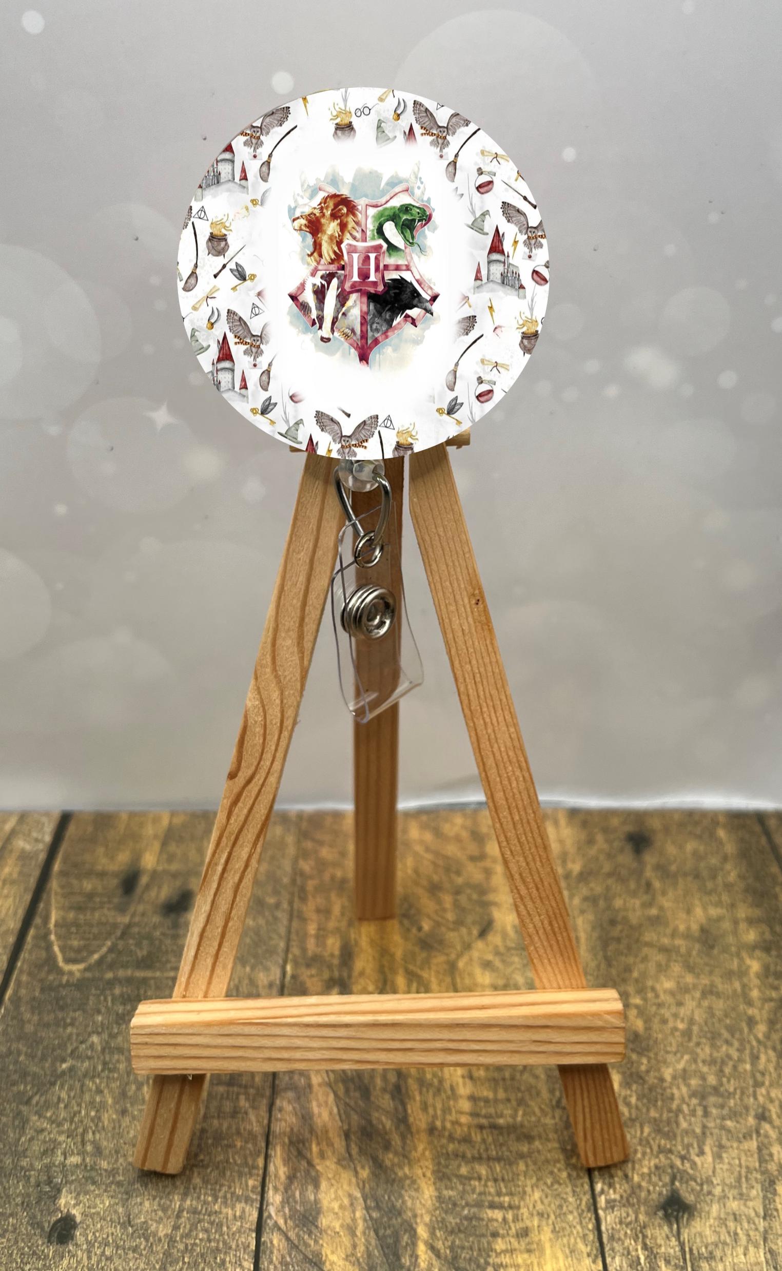 Wizard badge pulls featuring a colorful design with a lion and owl on a badge reel displayed on a wooden easel.