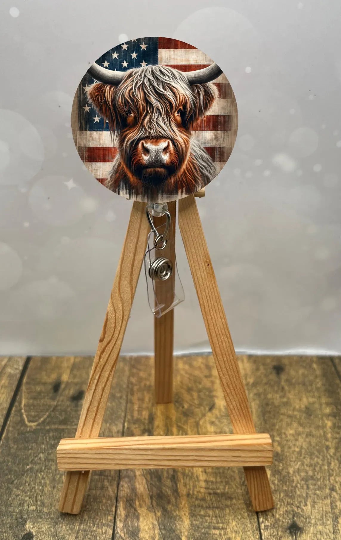 Highland cow badge pull featuring a cute highland cow face with an American flag background.