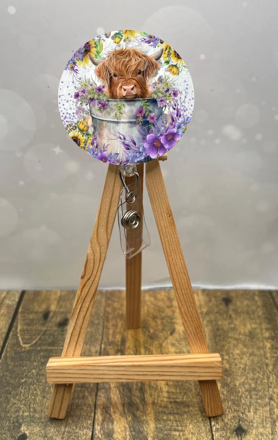 Highland cow badge pull featuring a fluffy cow face in a floral bucket, perfect for brightening workdays.
